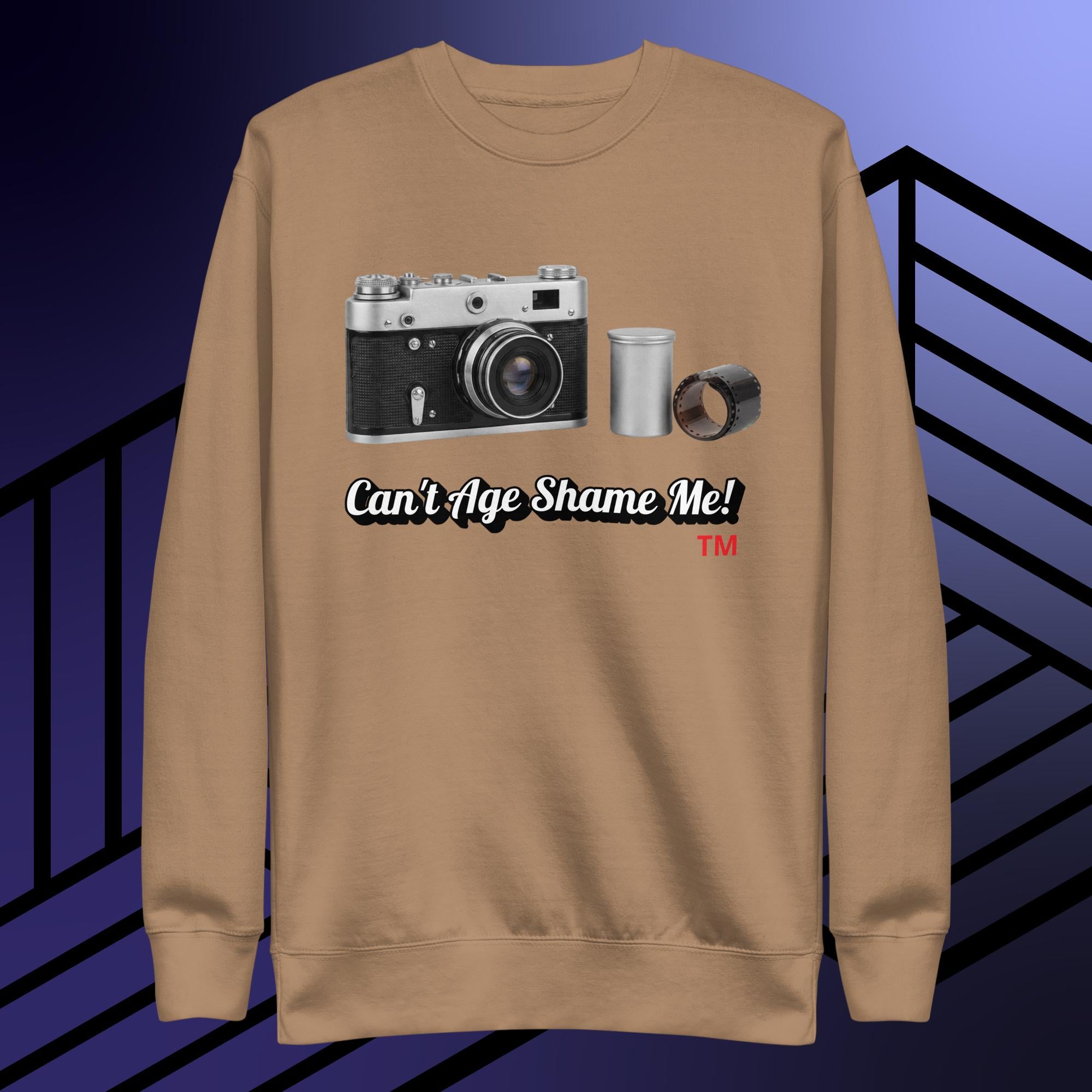 latte sweatshirt with camera graphic and text can't age shame me! on a blue and black striped background.