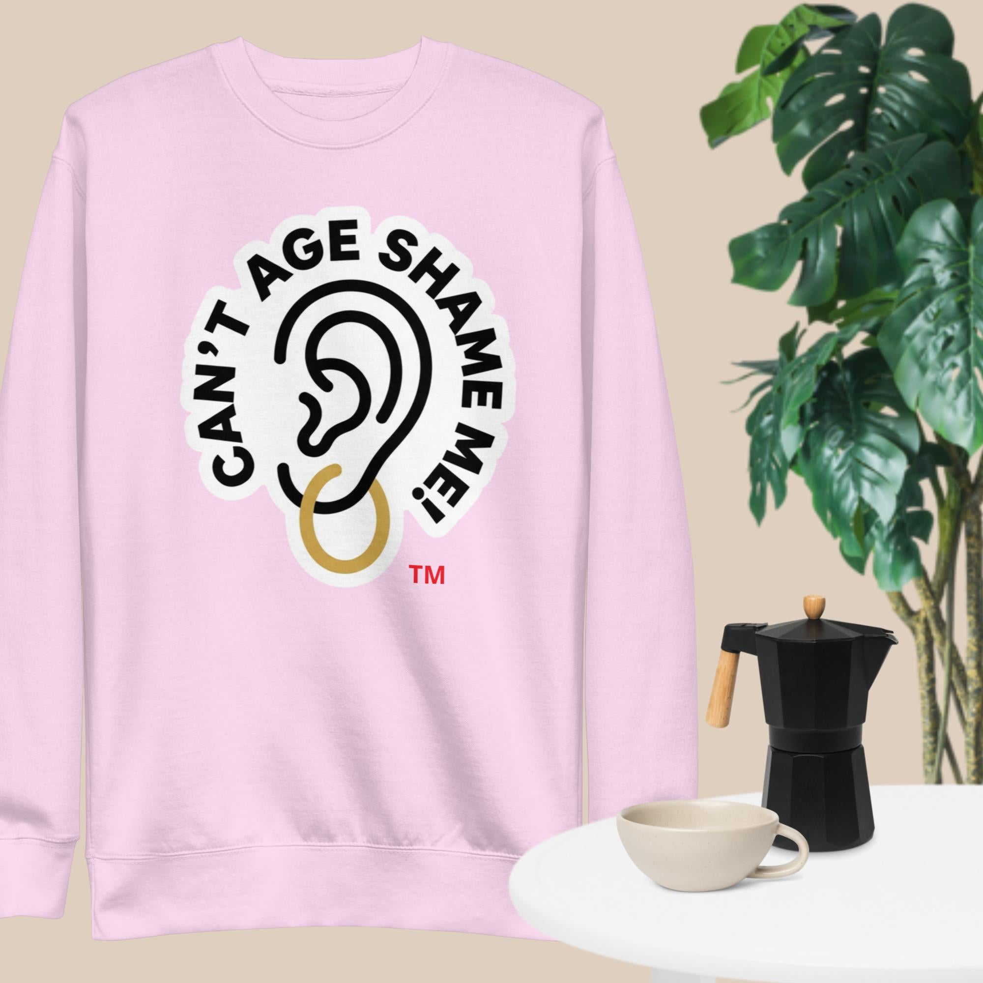 Light Lavender sweatshirt with 'Can't Age Shame Me' graphic on a beige background with a plant and coffee maker.