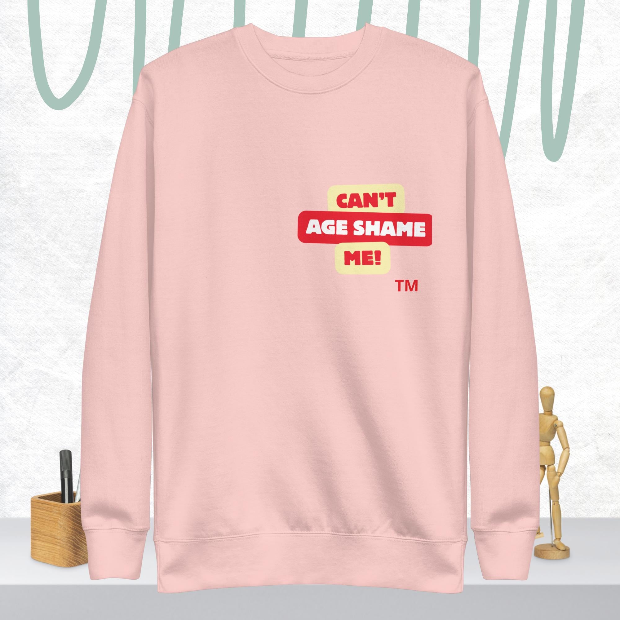 Light Pink sweatshirt with 'CAN'T AGE SHAME ME!' text logo on a light gray background