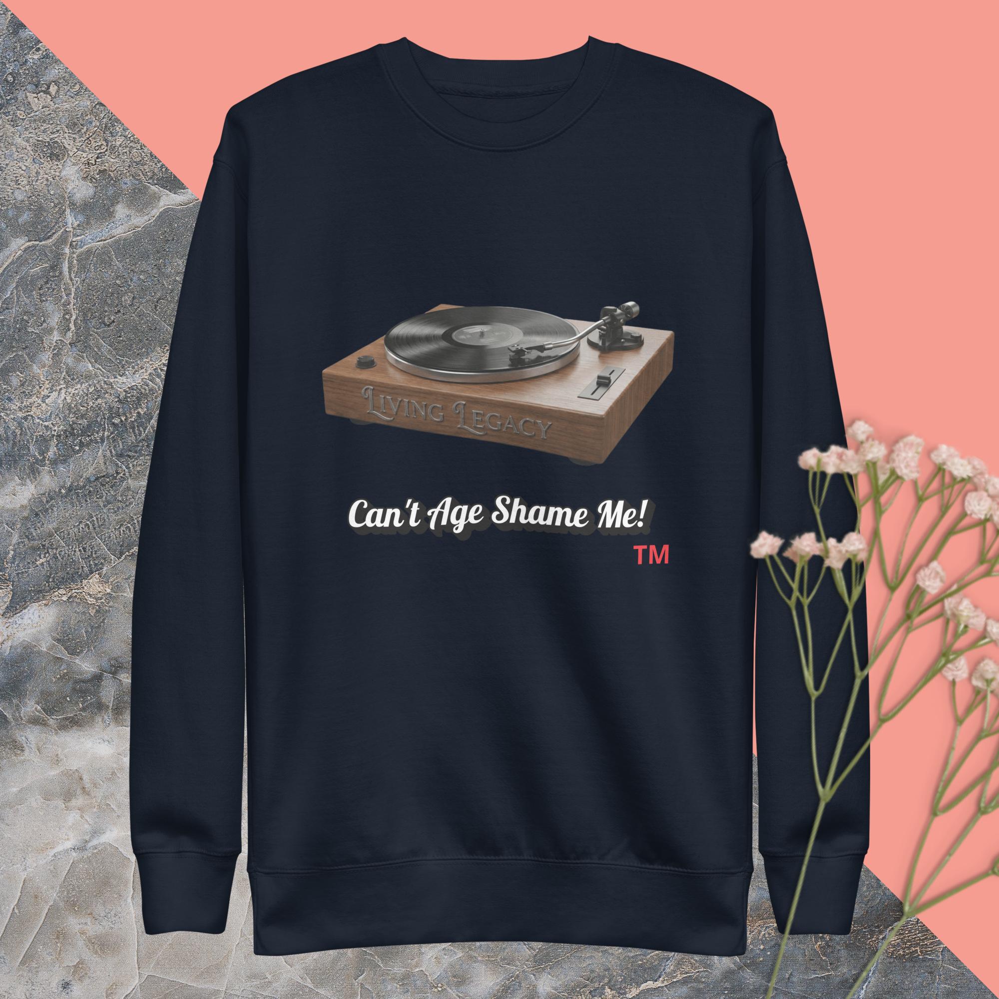 navy sweatshirt with a record player graphic and text can't age shame me ! on a pink and gray background