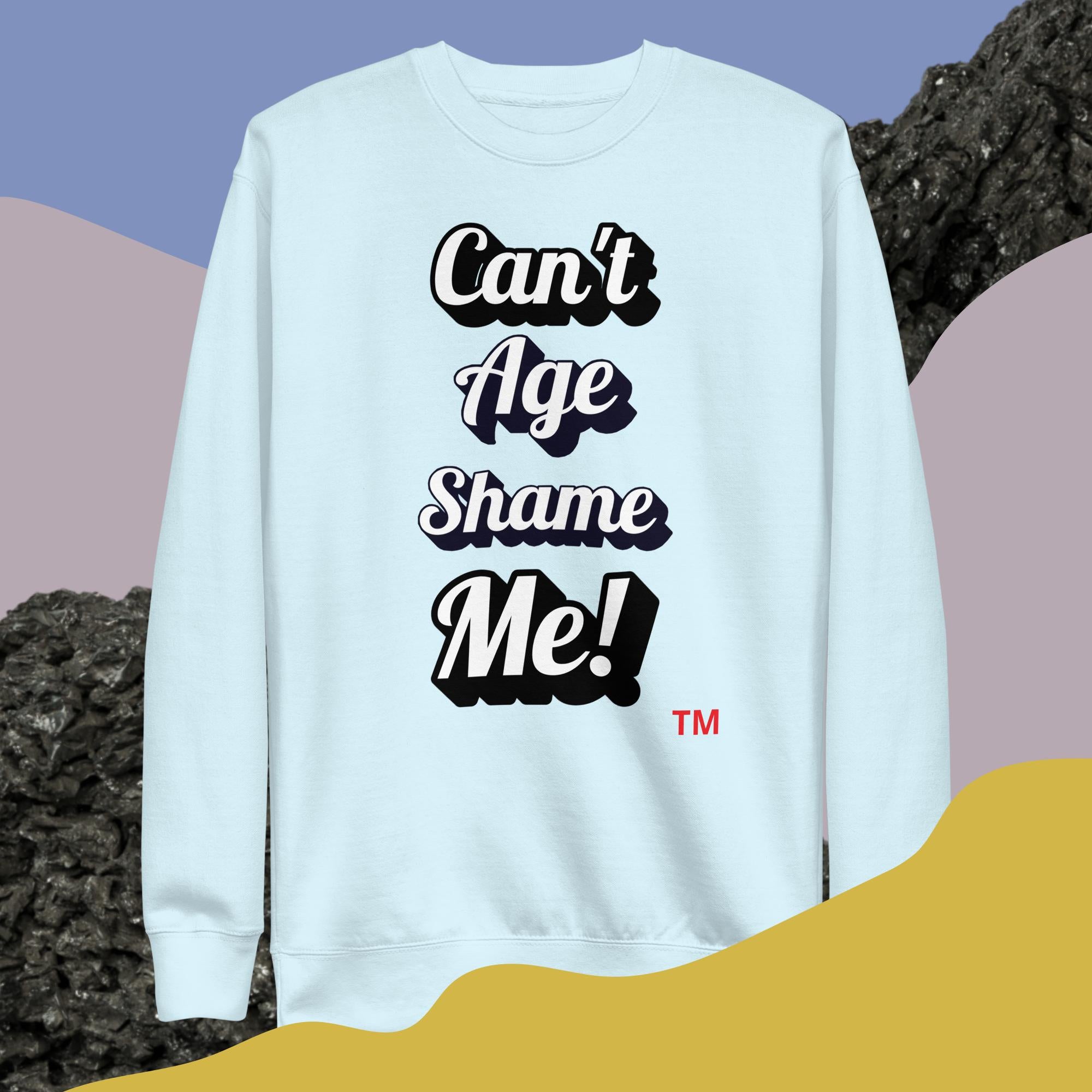 Light blue sweatshirt with 'Can't Age Shame Me!' text on a colorful abstract background