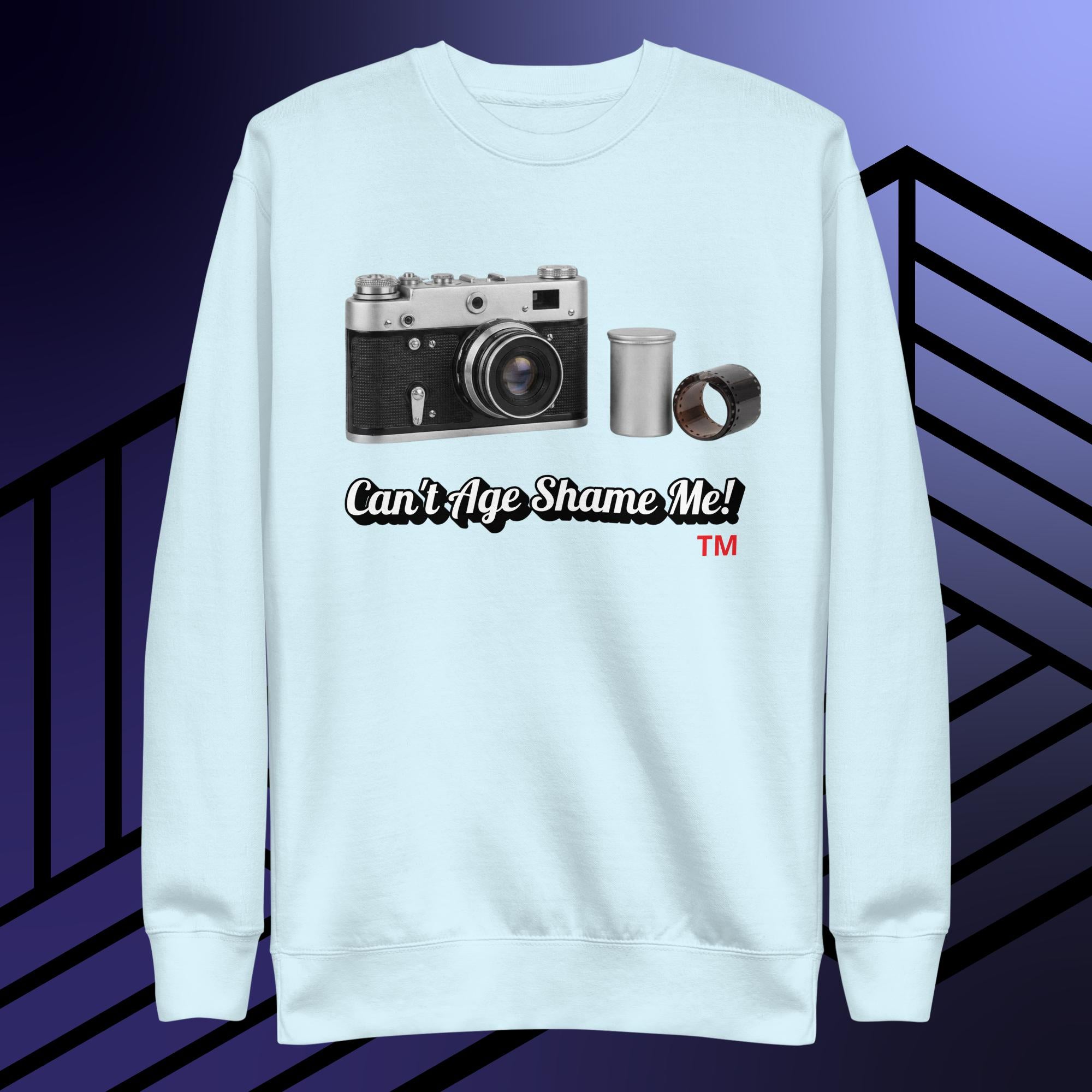 Light blue sweatshirt with camera graphic and text 'Can't Age Shame Me!' on a striped background