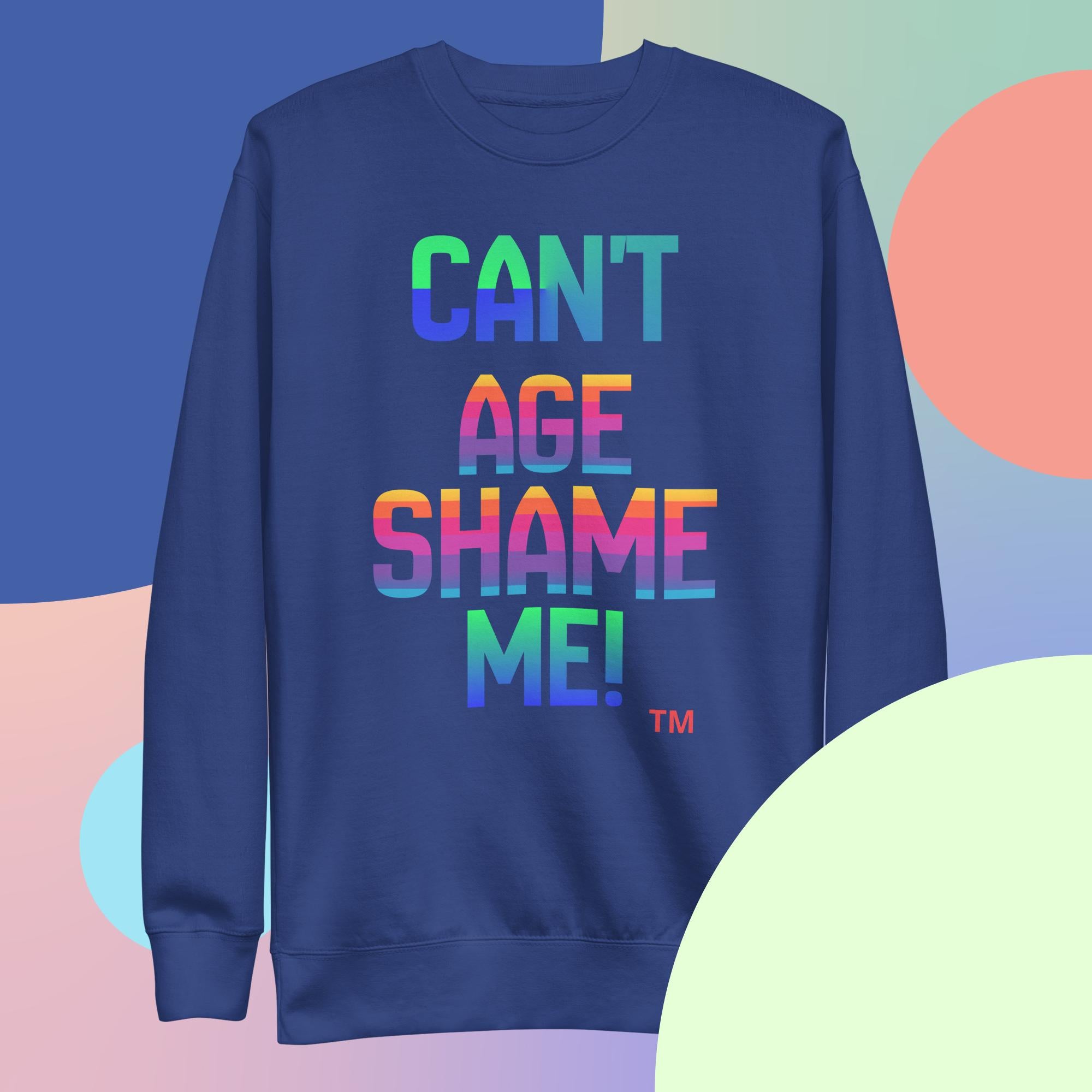 Blue sweatshirt with colorful text 'CAN'T AGE SHAME ME!' on a multicolored background