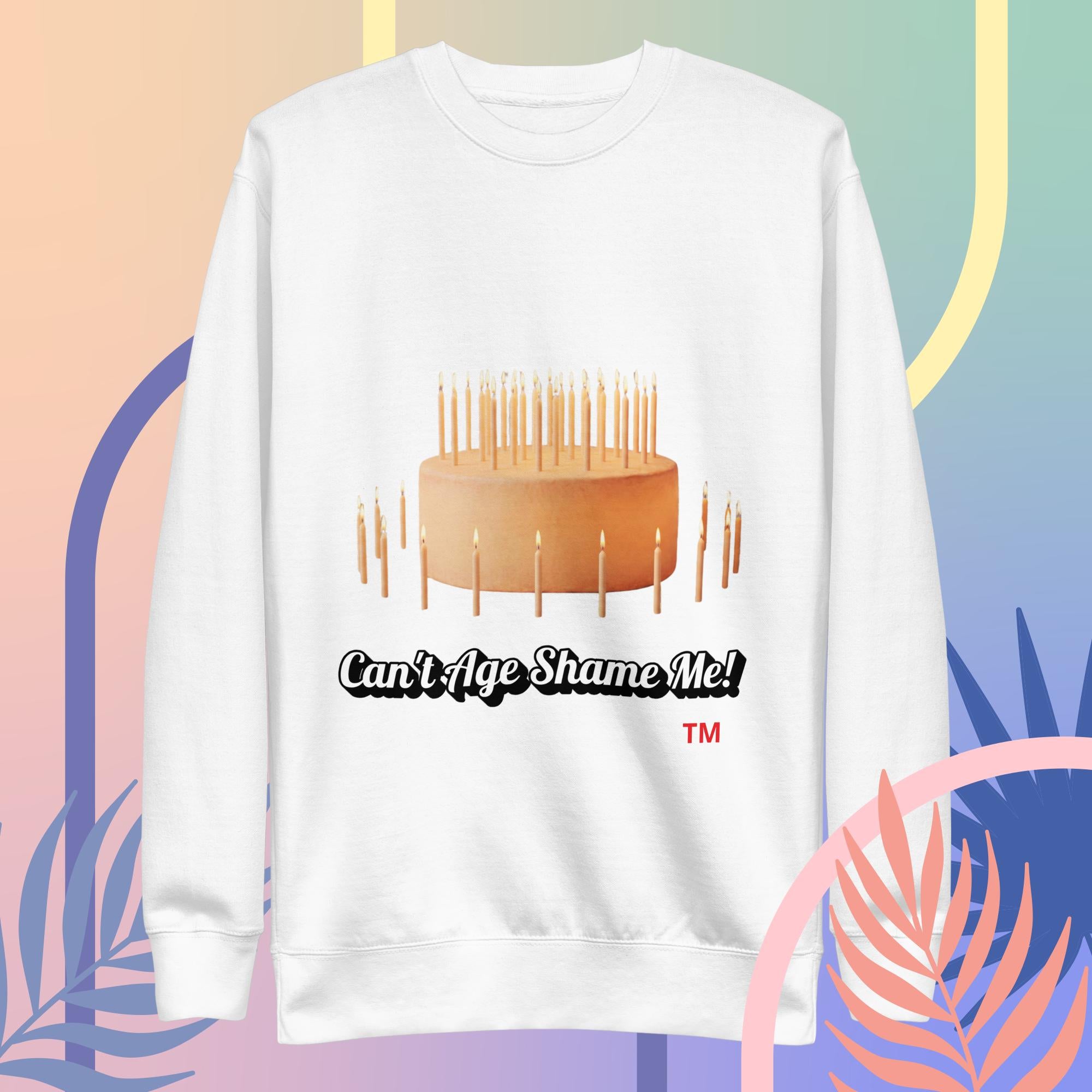 White sweatshirt with a cake and candles design and text 'Can't Age Shame Me!' on a colorful abstract background.