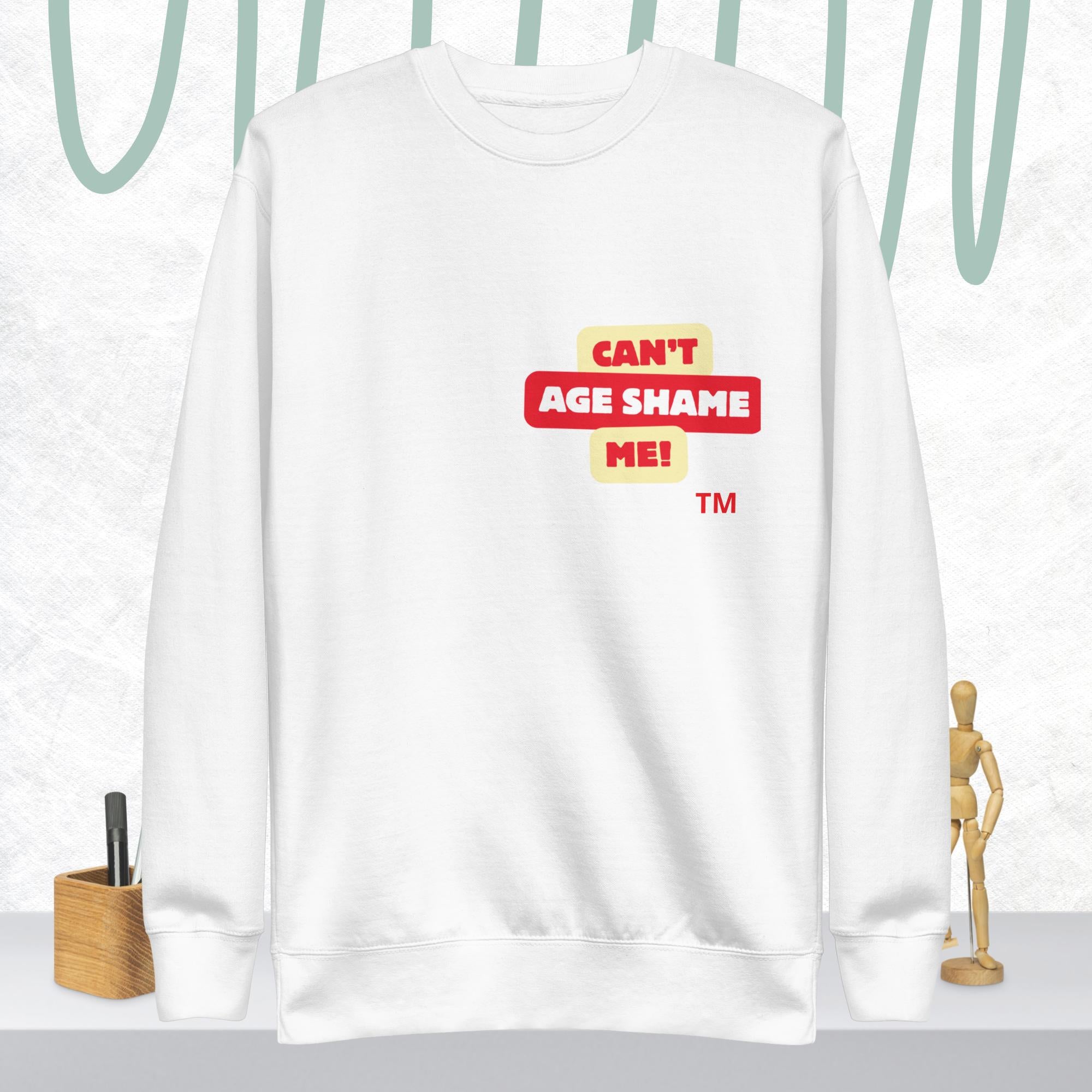 White sweatshirt with 'CAN'T AGE SHAME ME!' text logo on a light gray background