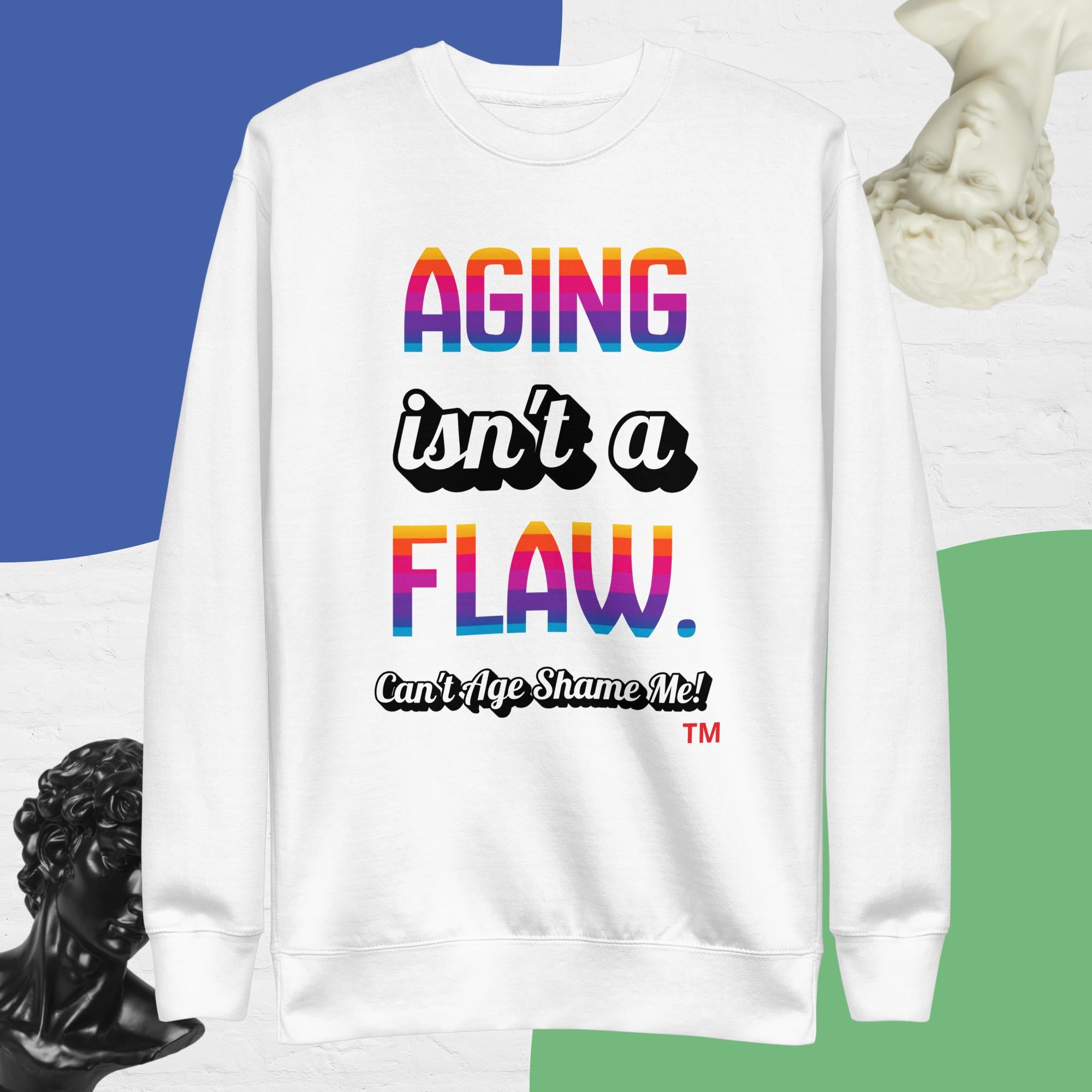 White sweatshirt with colorful text 'AGING isn't a FLAW. Can't Age Shame Me!' on a blue and green gradient background.