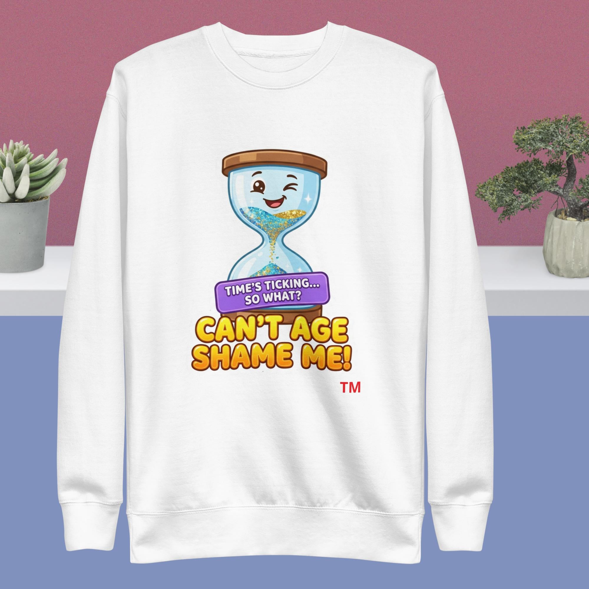 White sweatshirt with a cartoon hourglass design and humorous text on a pink and blue gradient background.