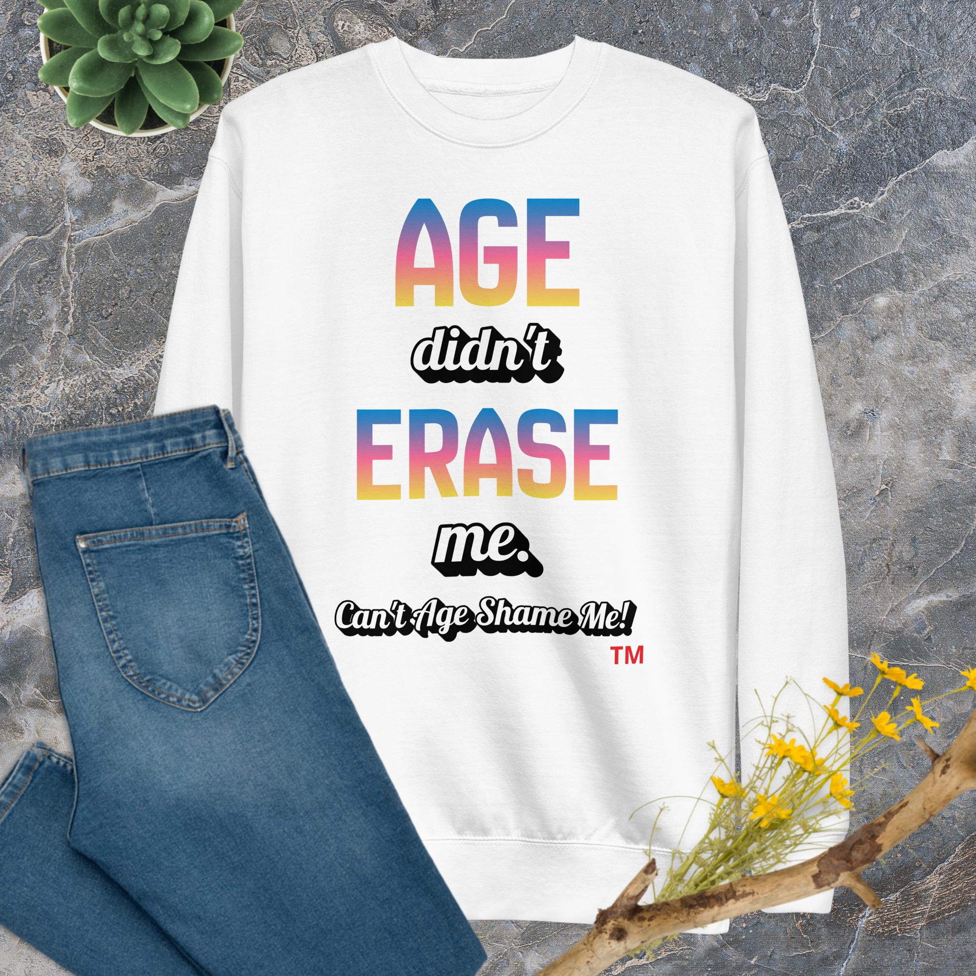 White sweatshirt with colorful text on a gray surface with jeans and flowers.