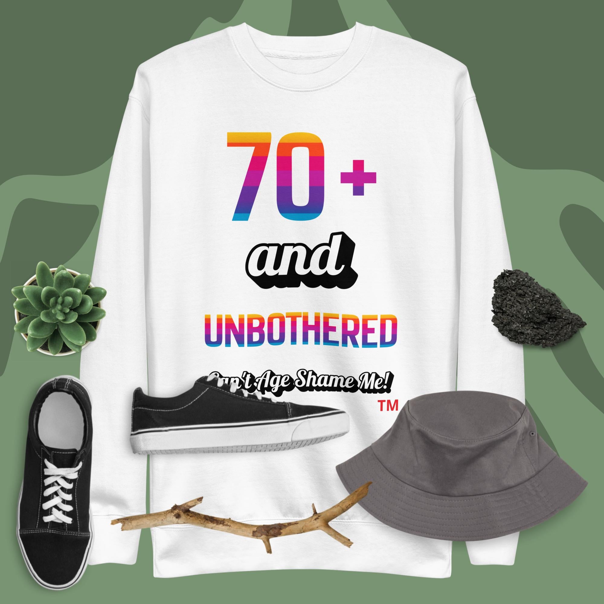 White t-shirt with colorful text design, black sneakers, gray bucket hat, and plant on a green background