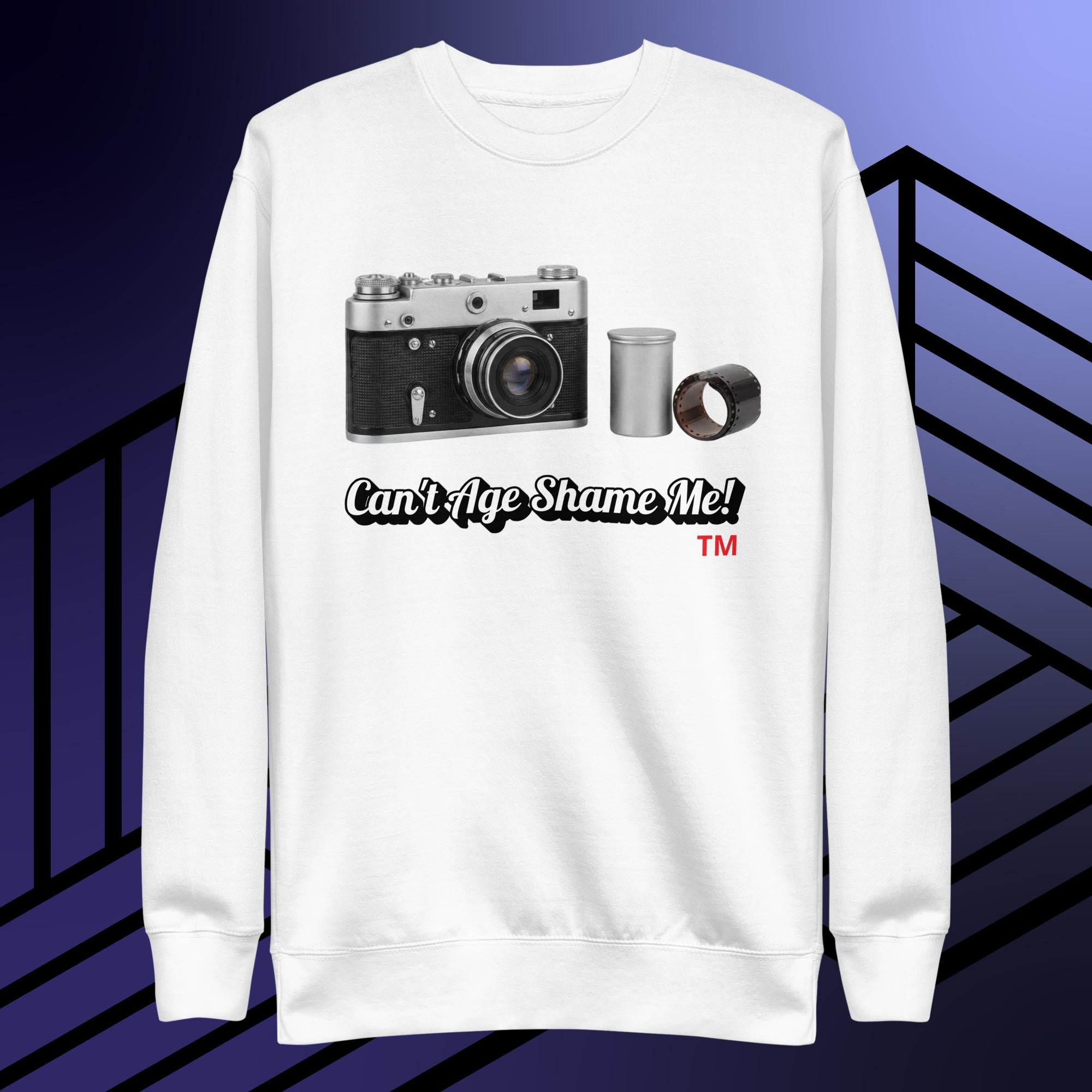 White sweatshirt with camera graphic and text 'Can't Age Shame Me!' on a striped background