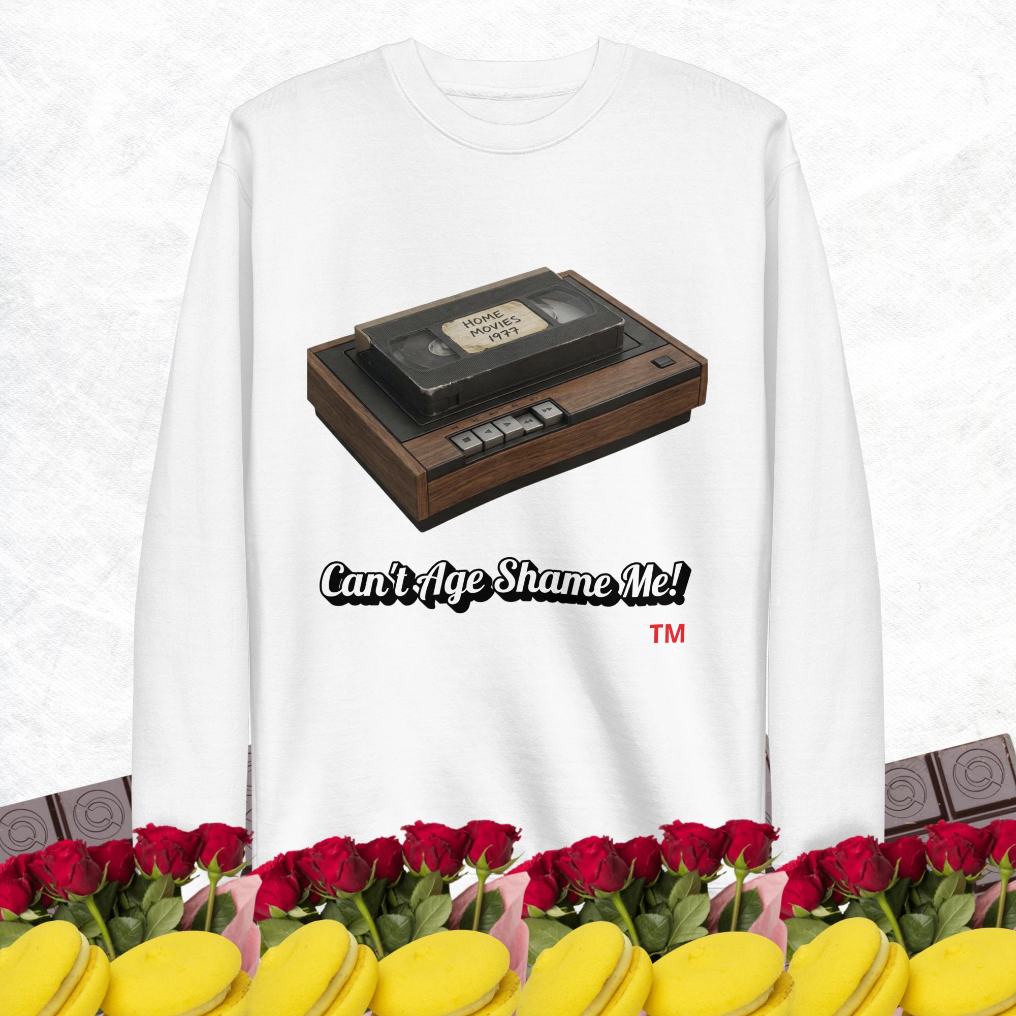 white sweatshirt with a vintage VHS player graphic and text 'Can't Age Shame Me!' on a white background.
