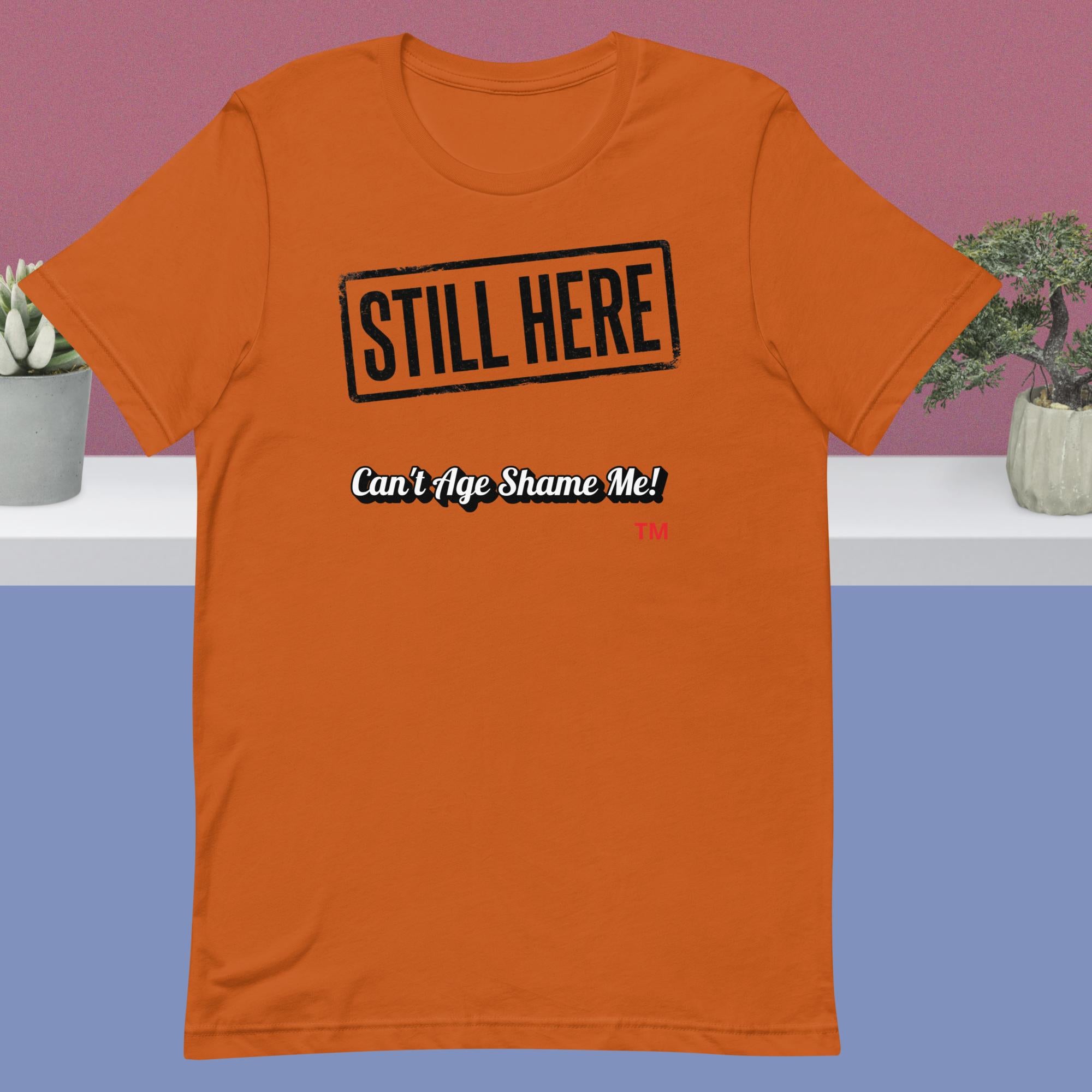 Autumn t-shirt with 'STILL HERE Can't Age Shame Me!' text on a plain background