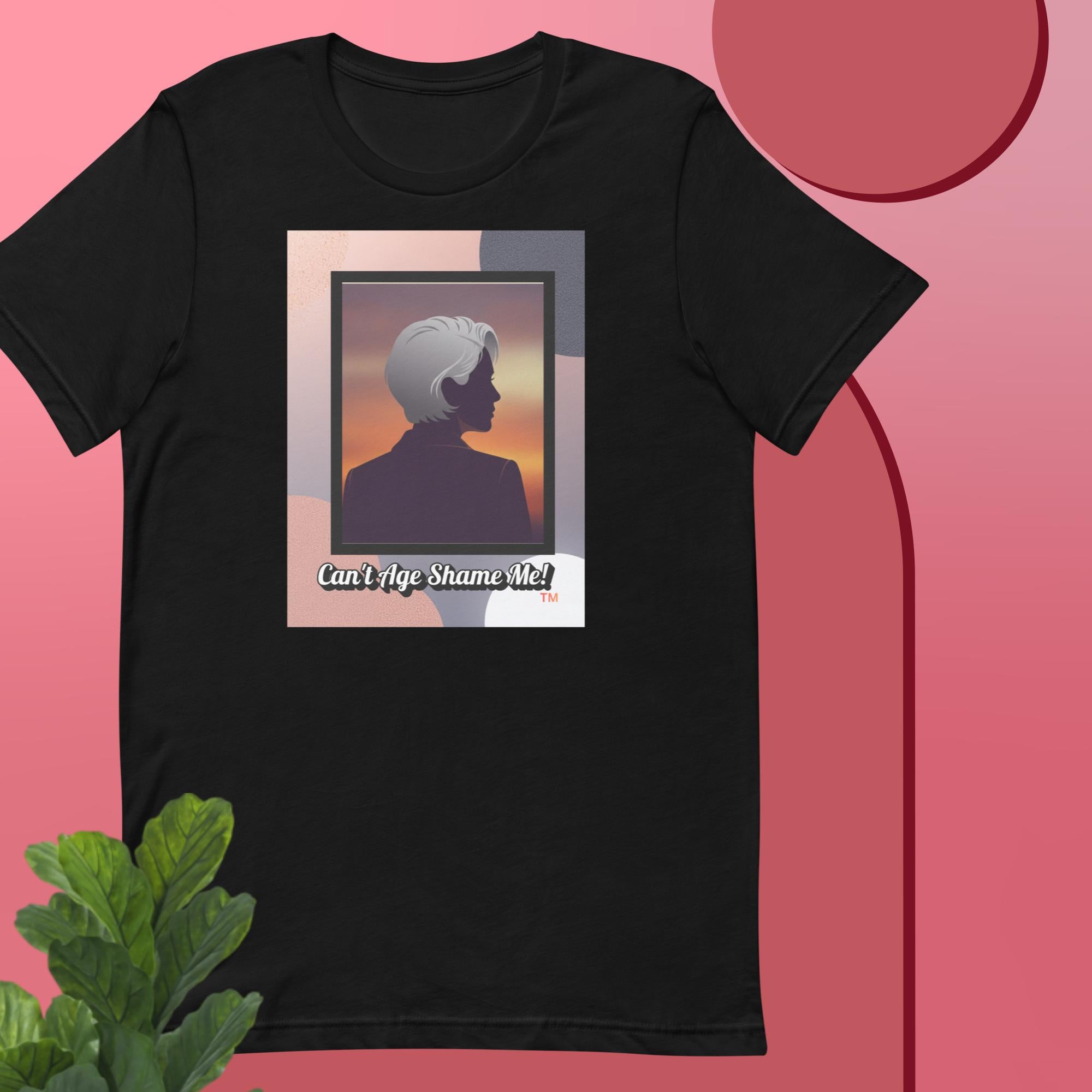 Black t-shirt with a graphic design featuring a woman with gray hair silhouette and text: Can’t Age Shame Me! on a pink background.


