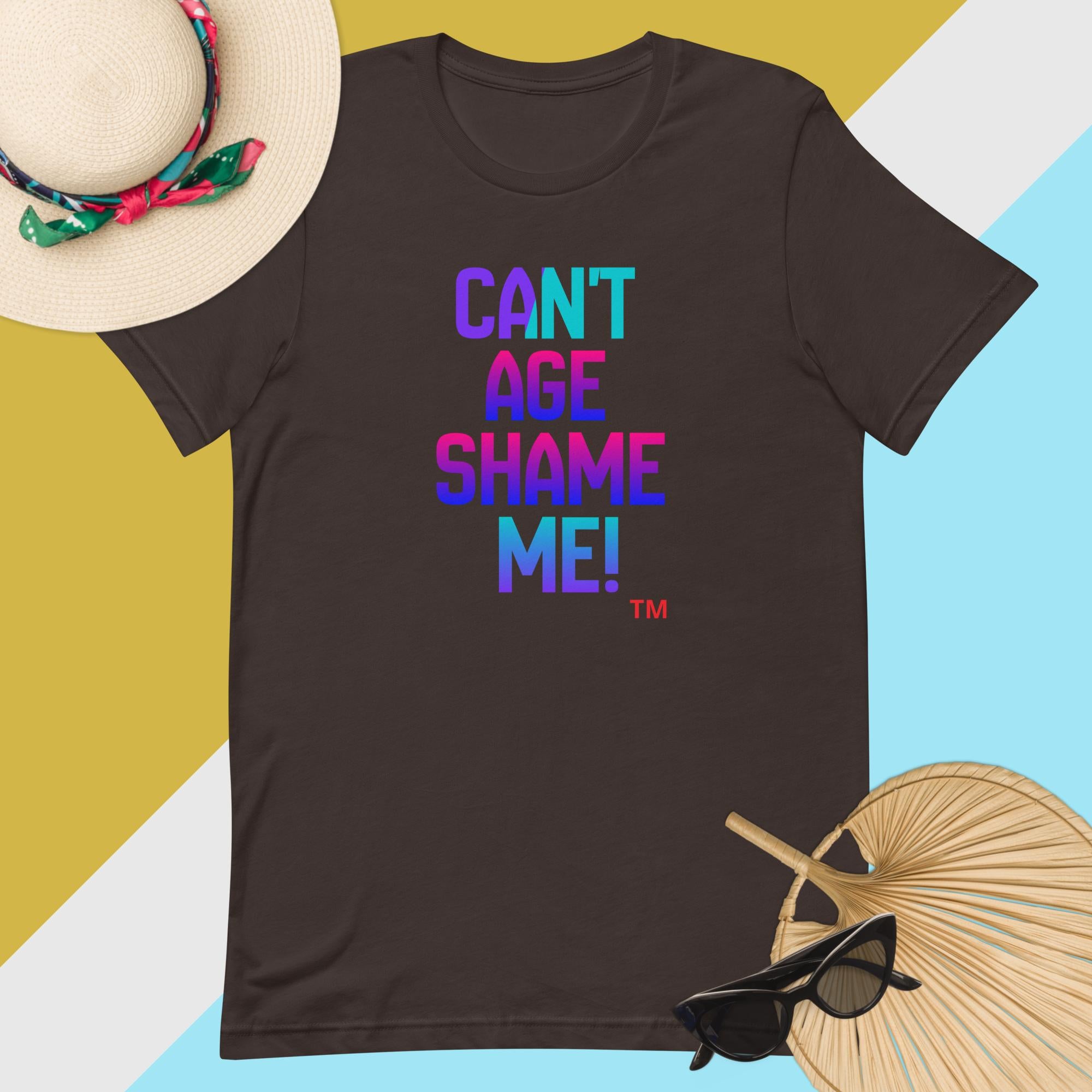 Black t-shirt with colorful text 'CAN'T AGE SHAME ME!' on a multicolored background with accessories.