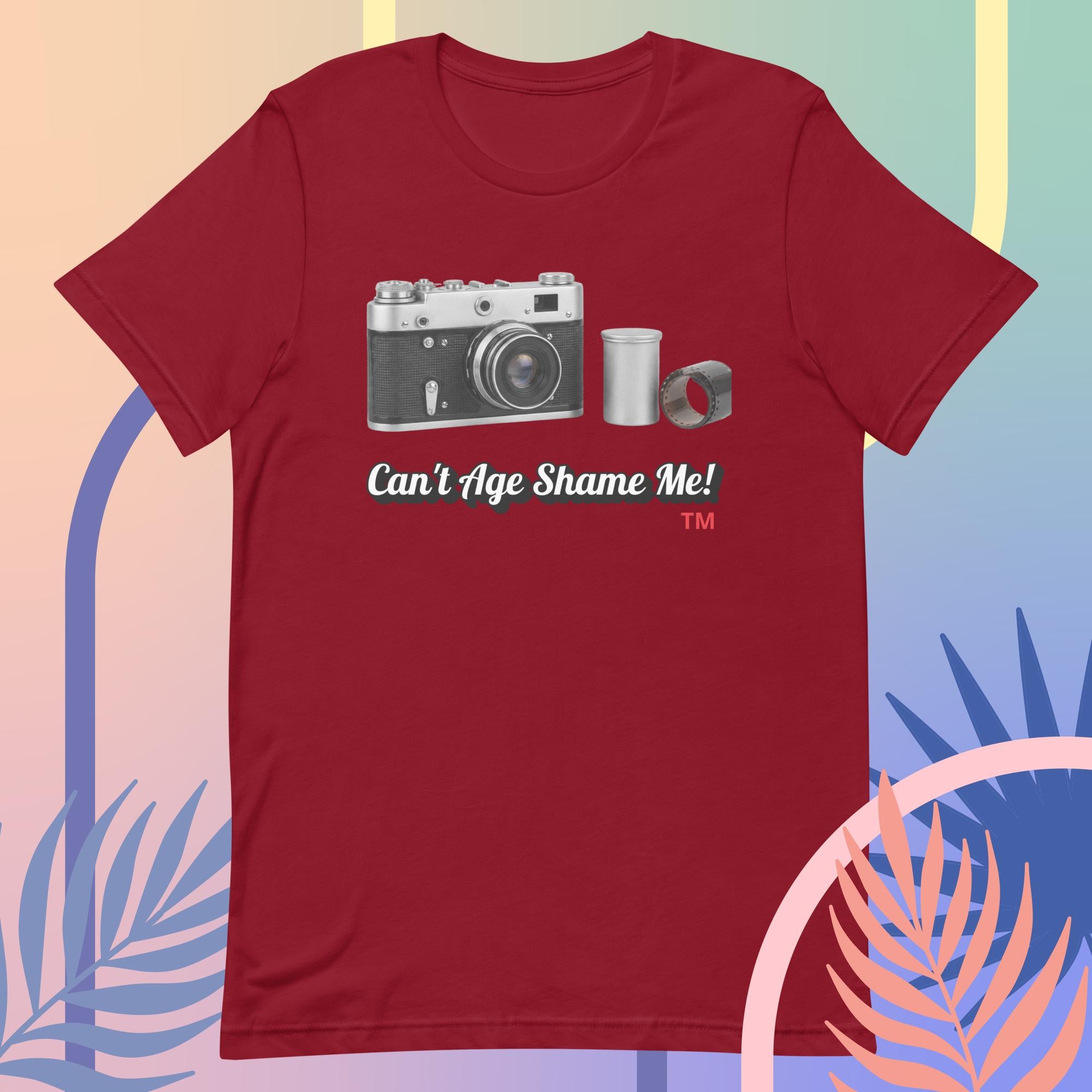 Red t-shirt with a camera graphic and text 'Can't Age Shame Me!' on a colorful background.