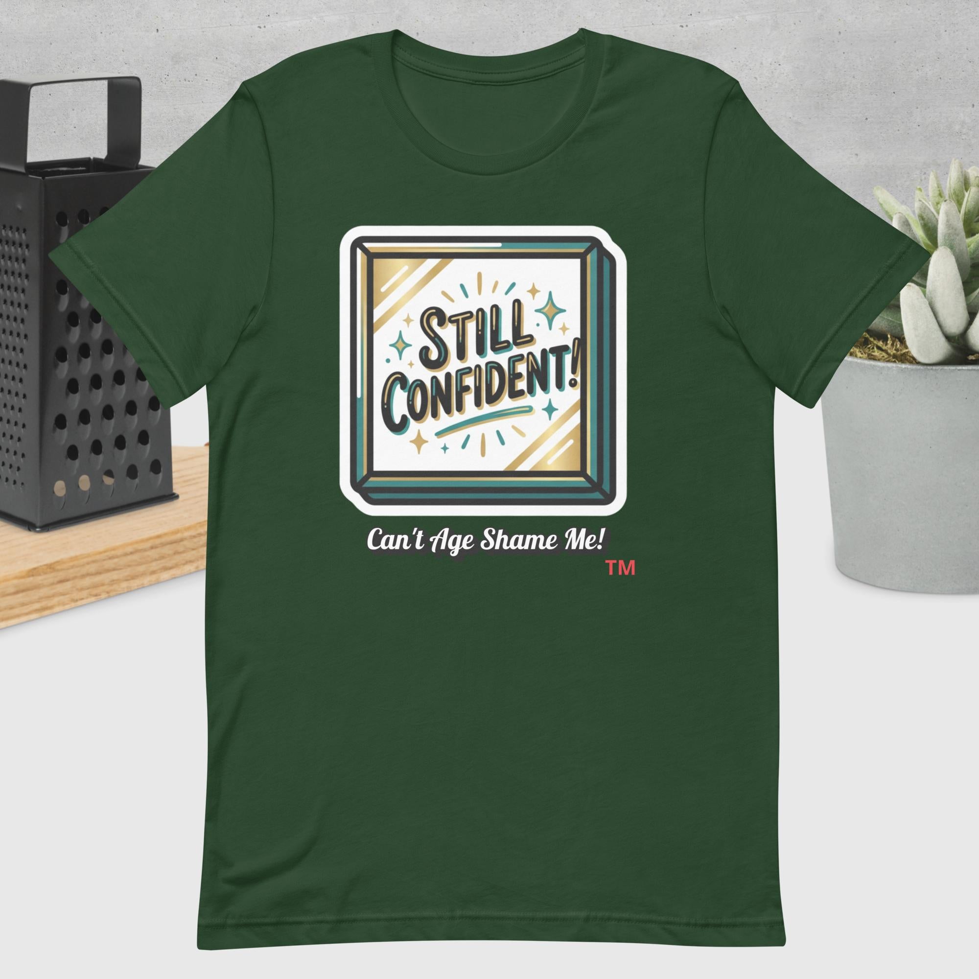 Forest Green t-shirt with 'Still Confident! Can't Age Shame Me!' graphic design on a neutral background.