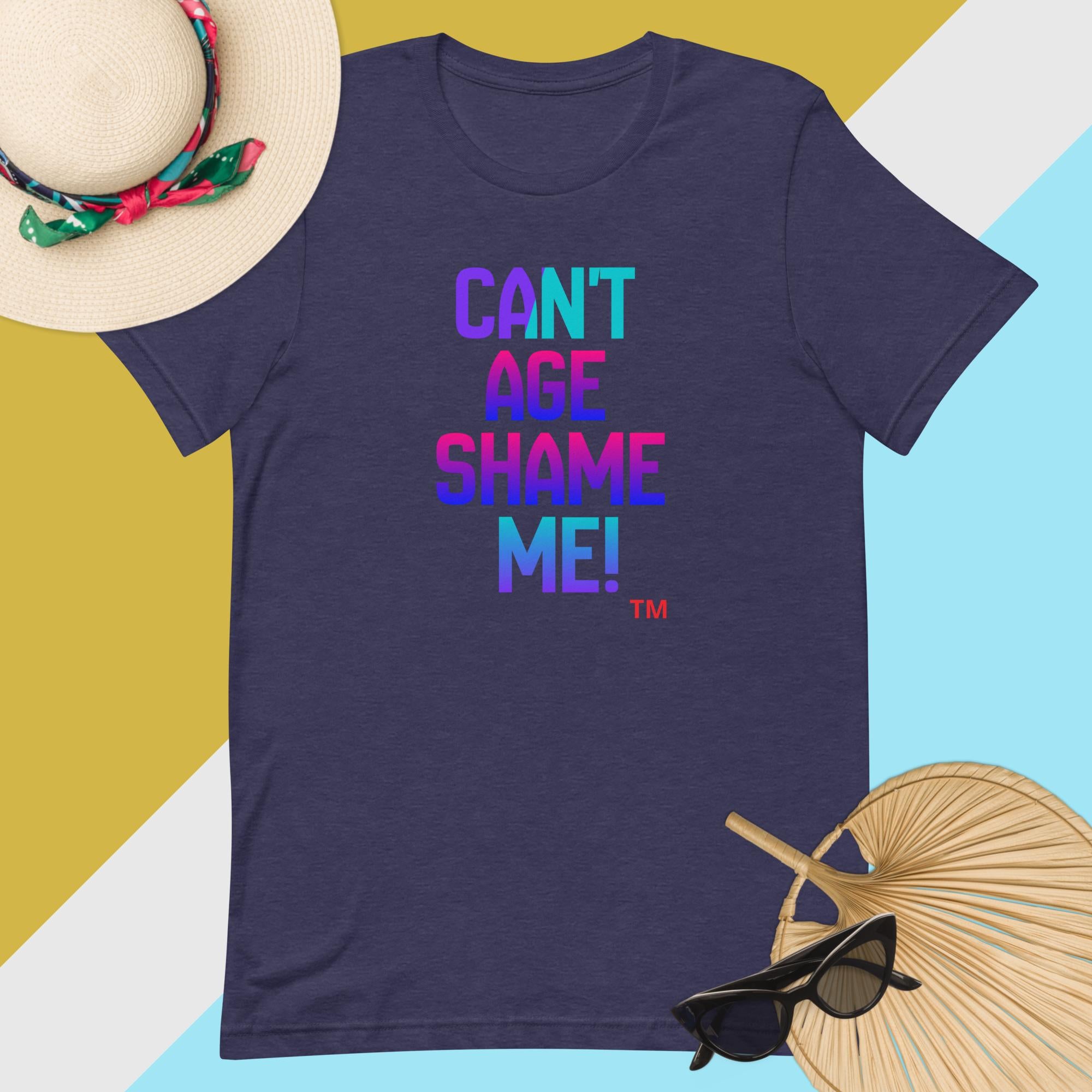 Navy blue t-shirt with colorful text 'CAN'T AGE SHAME ME!' on a multicolored background with accessories.