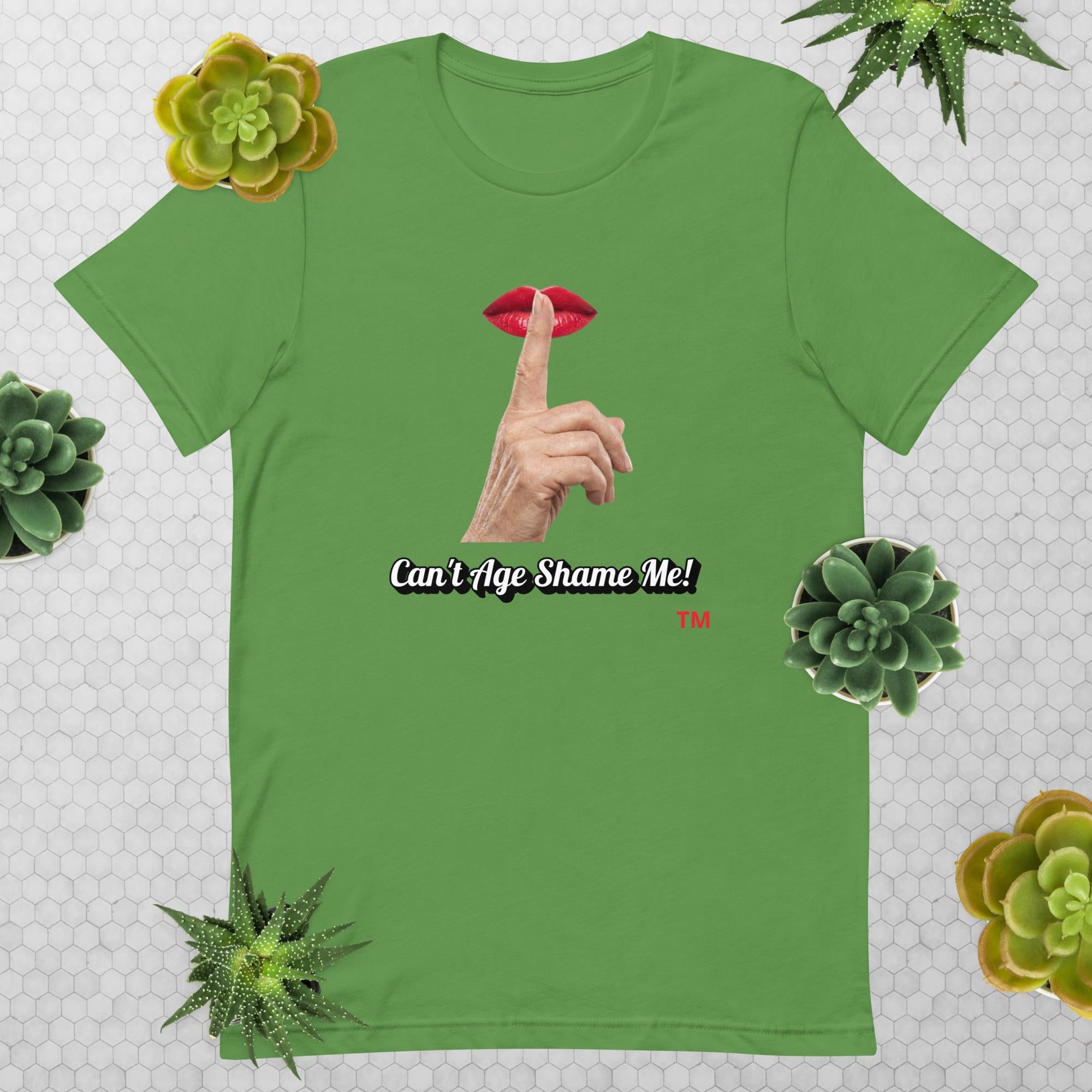 Leaf t-shirt with graphic design of finger on mouth and text 'CAN'T AGE SHAME ME!' text logo on a light gray background with succulents.