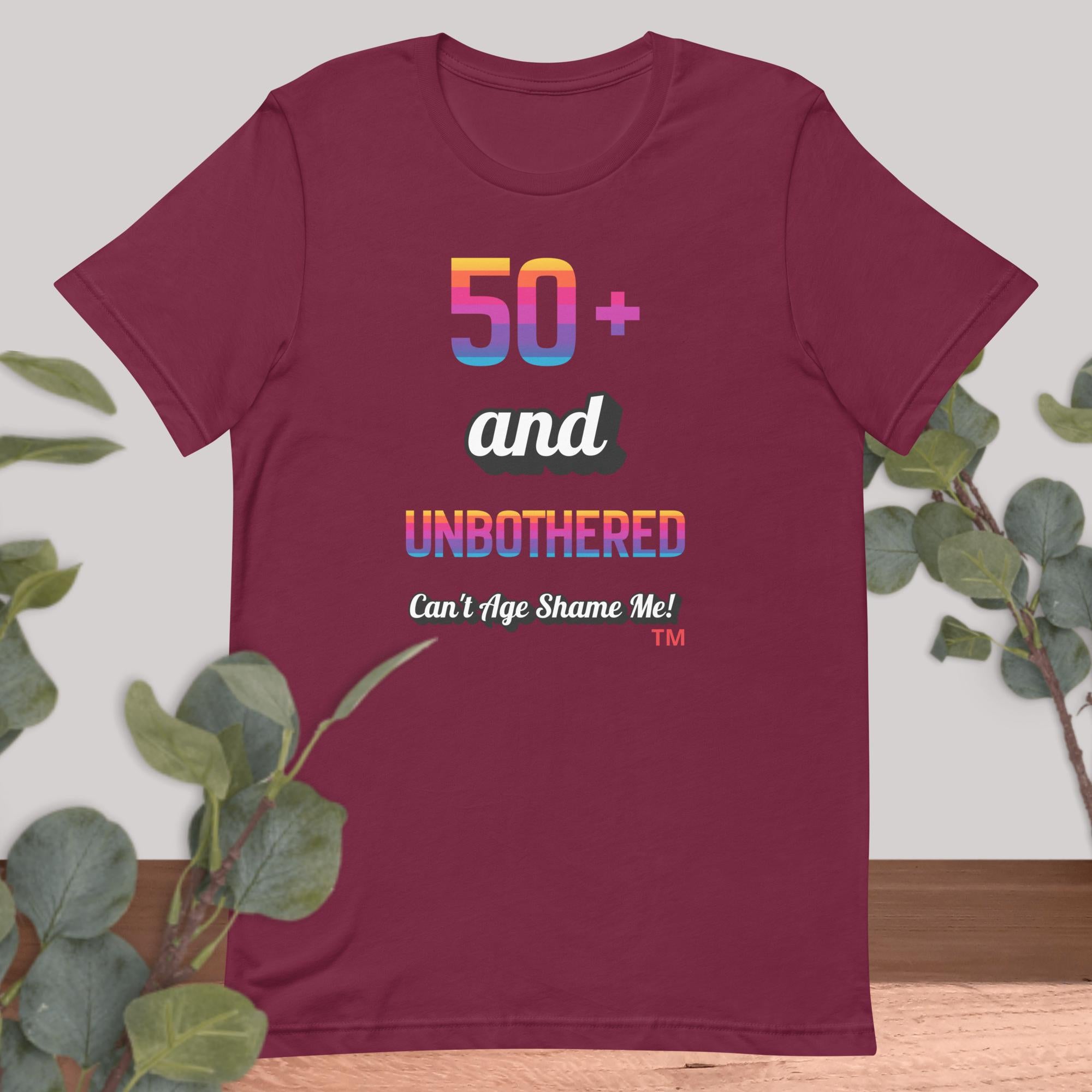 Maroon t-shirt with colorful text design on a light background with greenery