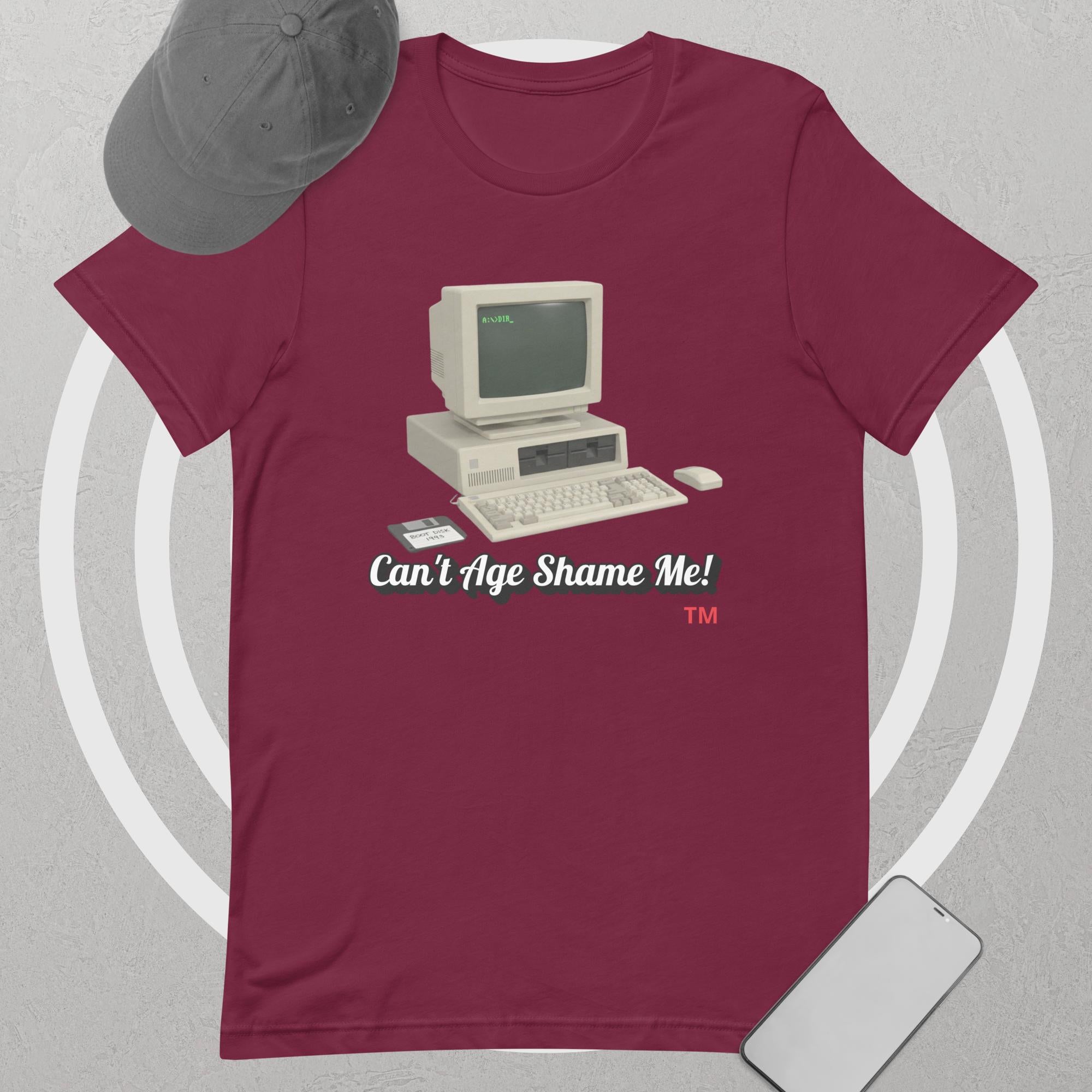 Maroon t-shirt with vintage computer graphic and text 'Can't Age Shame Me' on a gray background
