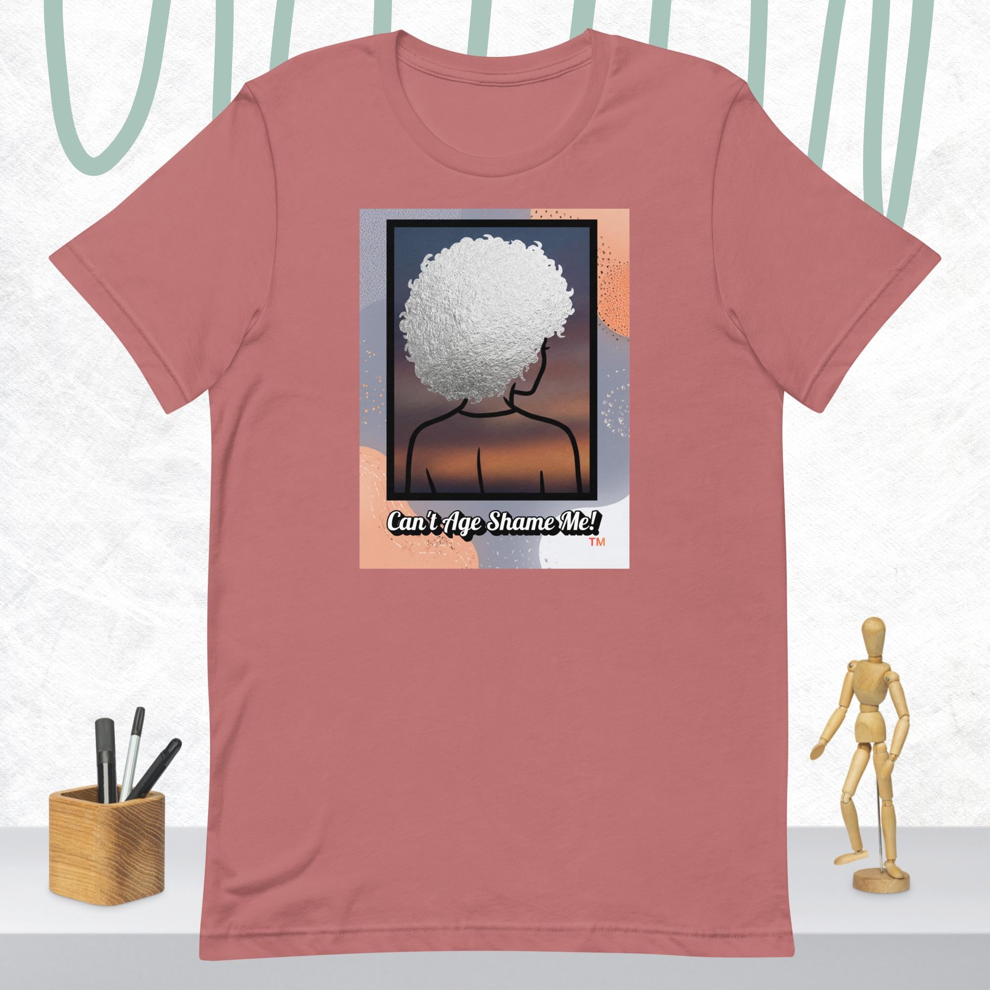 Mauve t-shirt with a graphic of a person with an afro and text 'Can't Age Shame Me!' on a white background.