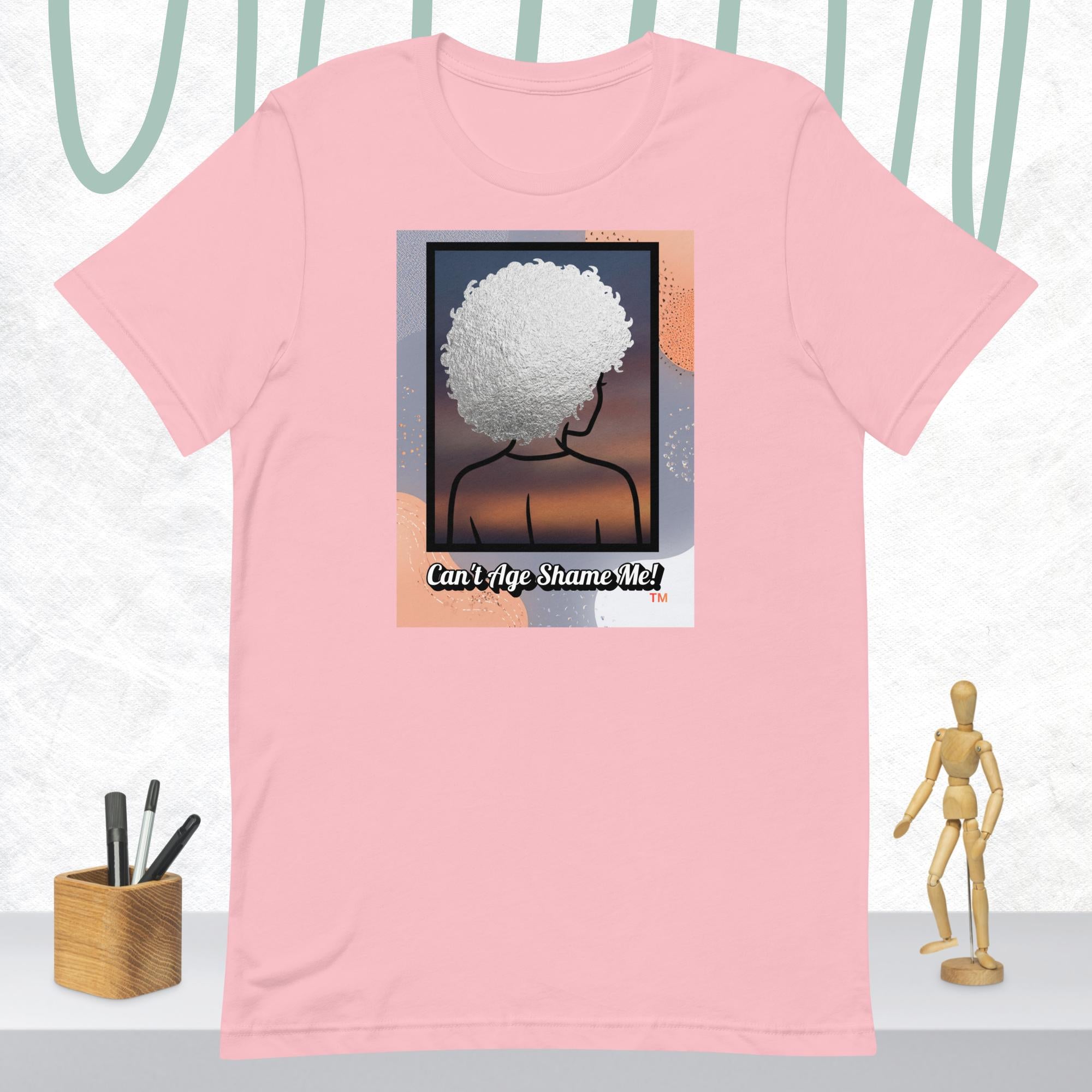 Pink t-shirt with a graphic of a person with an afro and text 'Can't Age Shame Me!' on a white background.