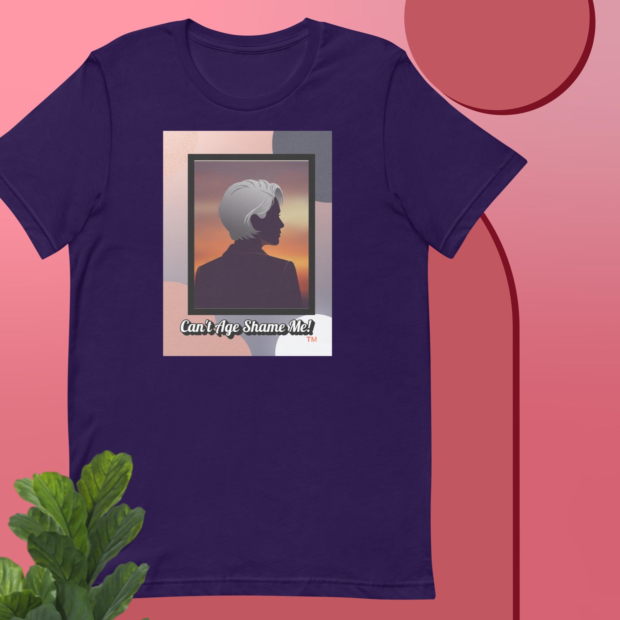 Purple t-shirt with a graphic design featuring a woman with gray hair silhouette and text: Can’t Age Shame Me! on a pink background.


