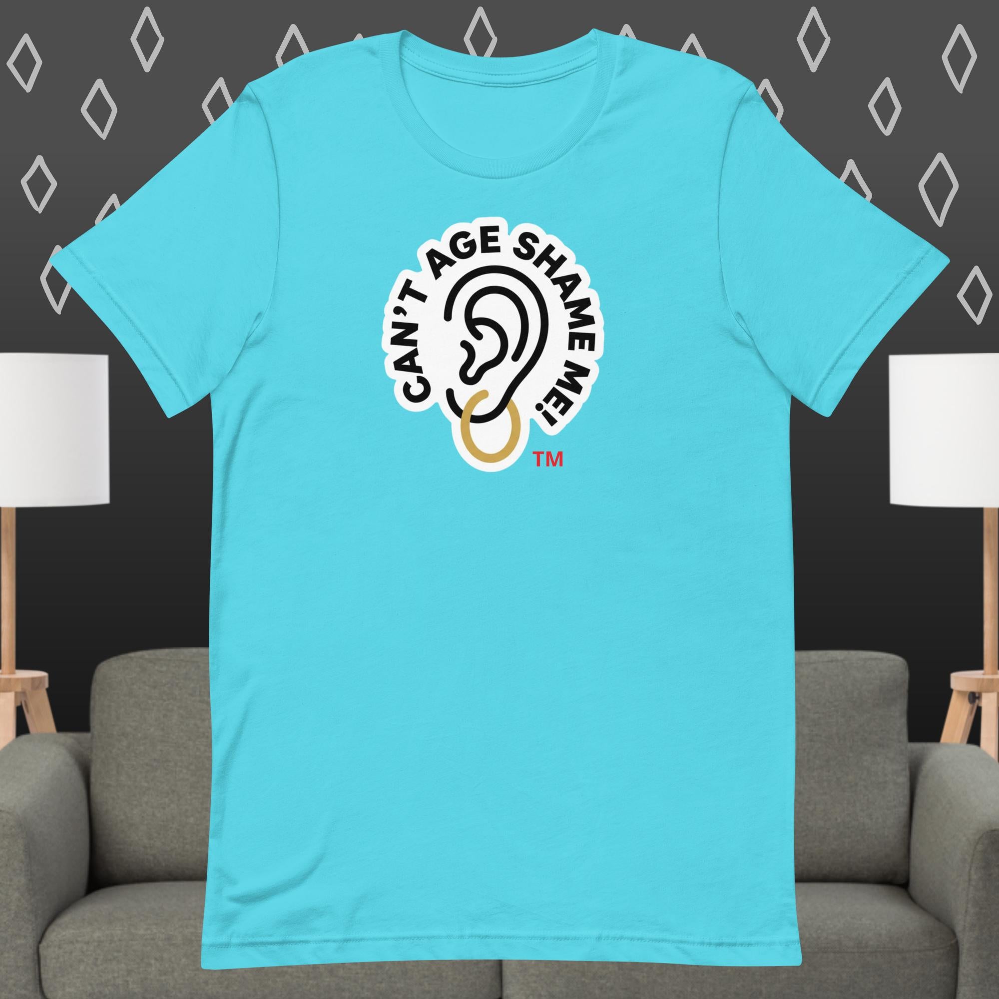 Mint Blue t-shirt with 'Can't Age Shame Me' graphic on a gray couch and lamp background