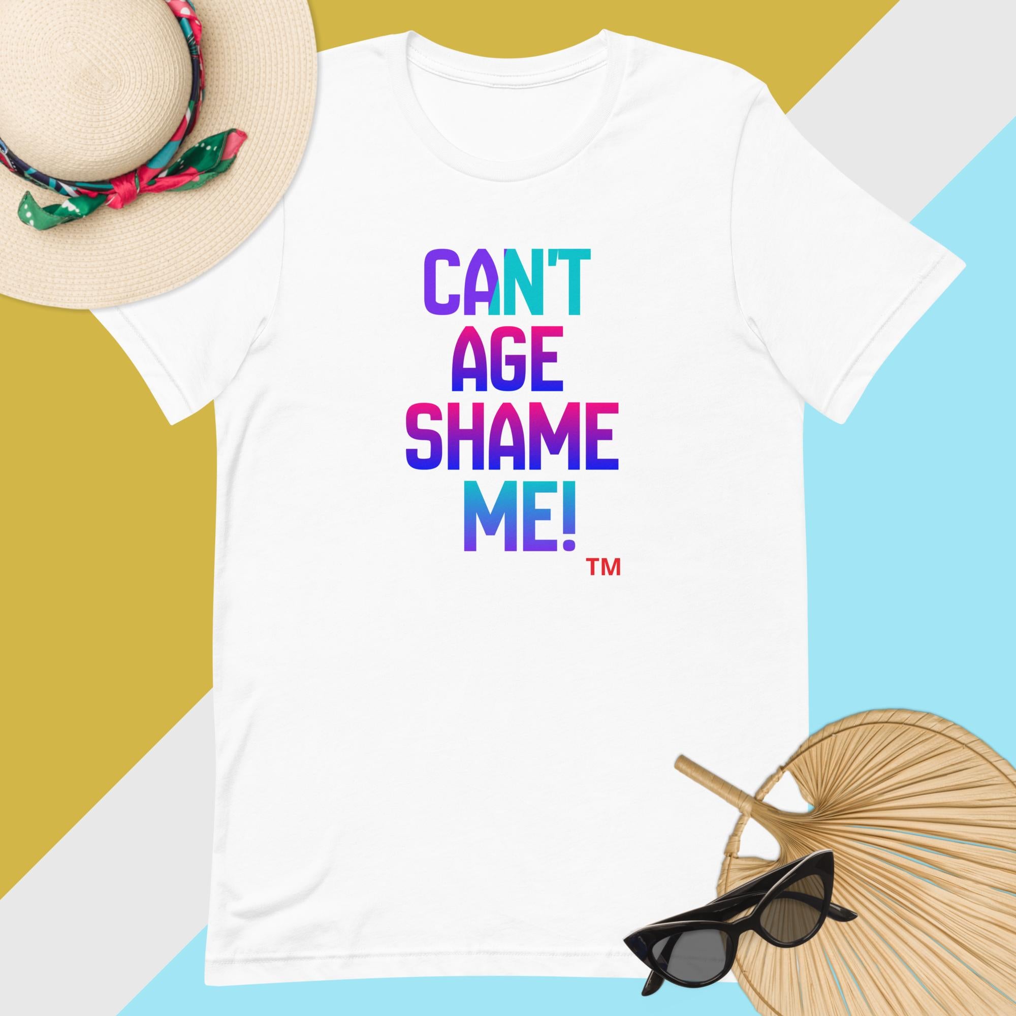 White t-shirt with colorful text 'CAN'T AGE SHAME ME!' on a yellow and blue geometric background.