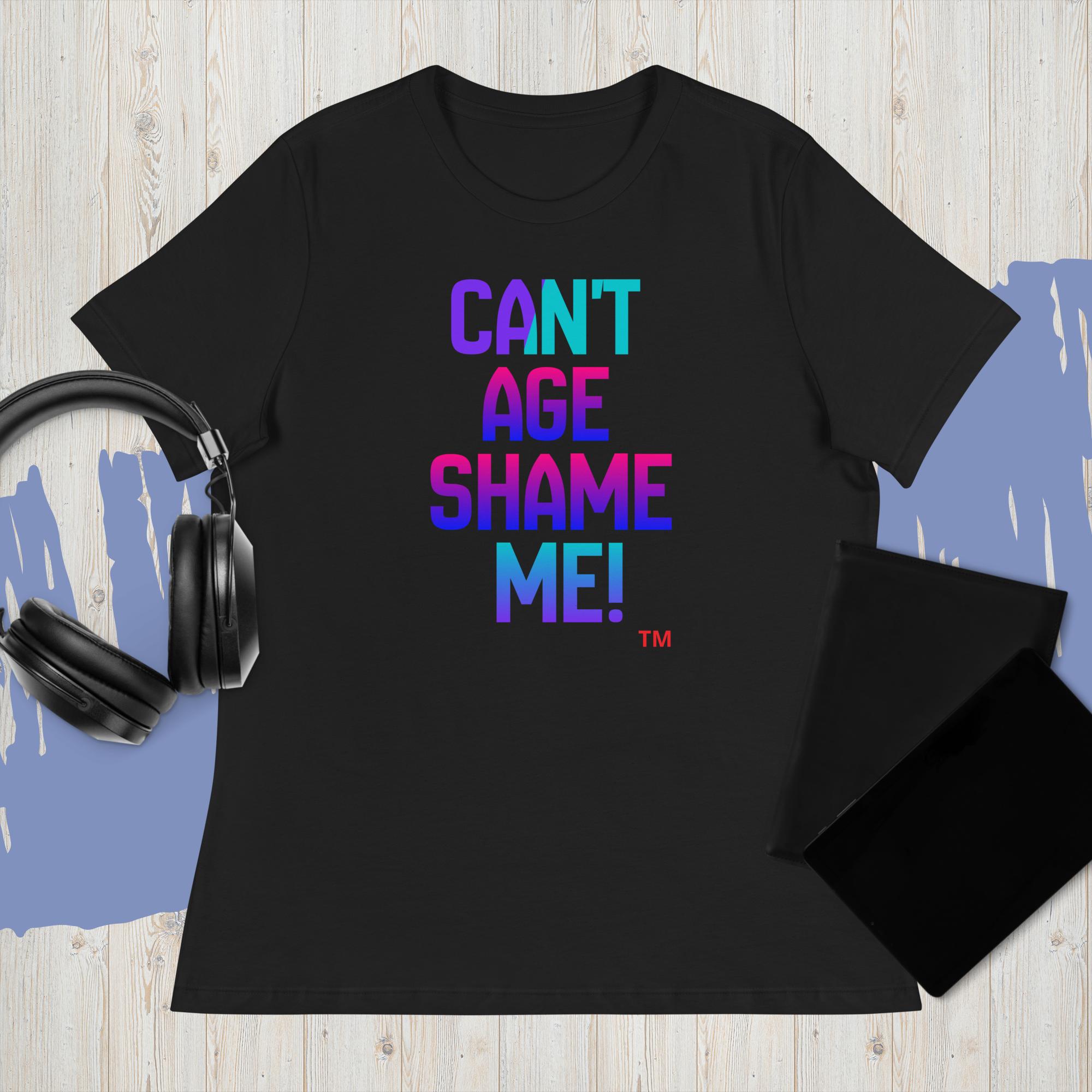 Black t-shirt with colorful text 'CAN'T AGE SHAME ME!' on a wooden surface with headphones.