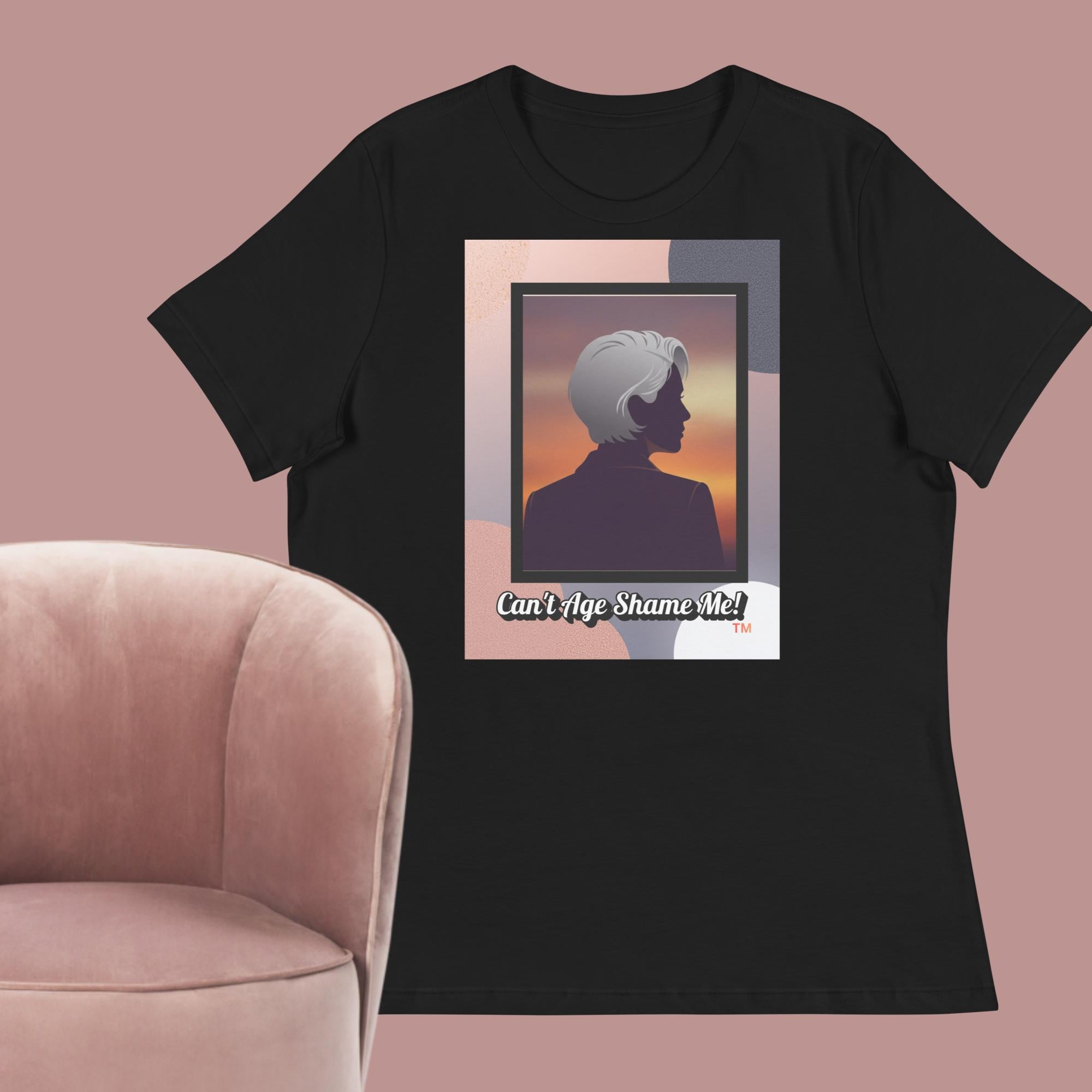 Black T-shirt with a graphic design featuring a woman with gray hair silhouette and text: Can’t Age Shame Me! surrounded by a pink chair against a pink background.

