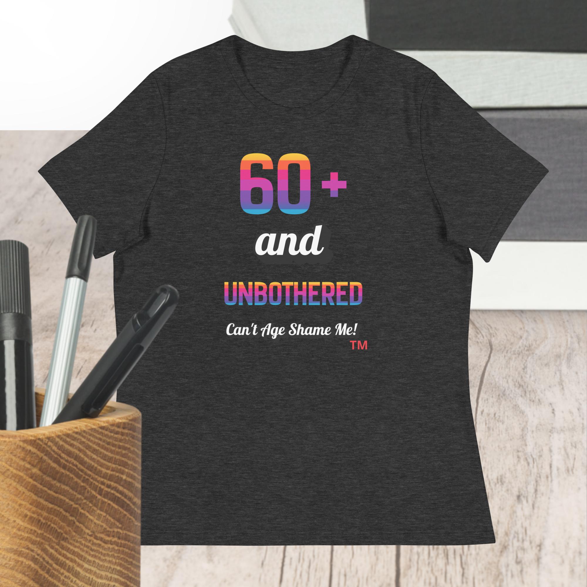 Dark gray t-shirt with colorful text design on a wooden surface with pens.