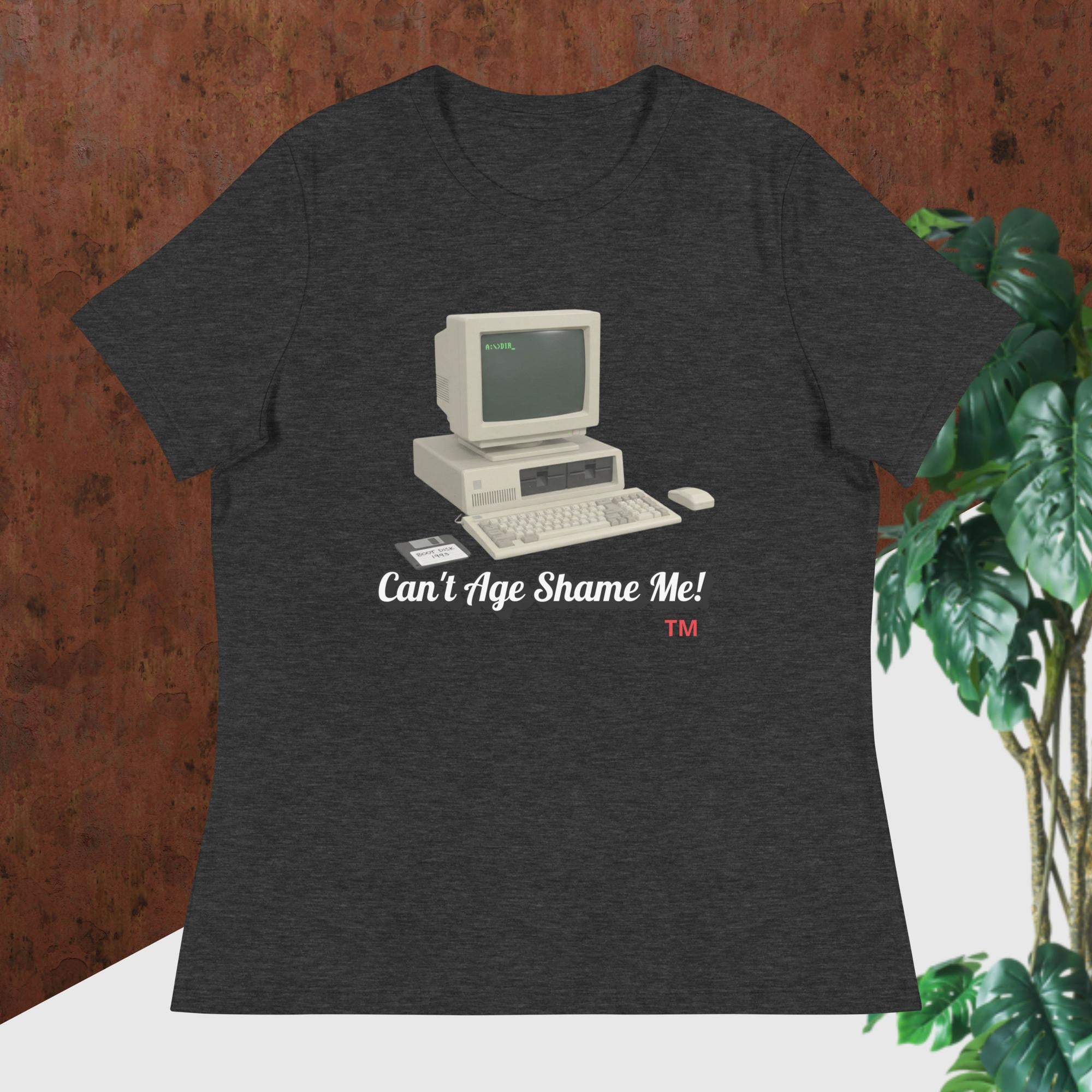 dark gray heather t-shirt with vintage computer graphic and text 'Can't Age Shame Me!' on a wooden surface.