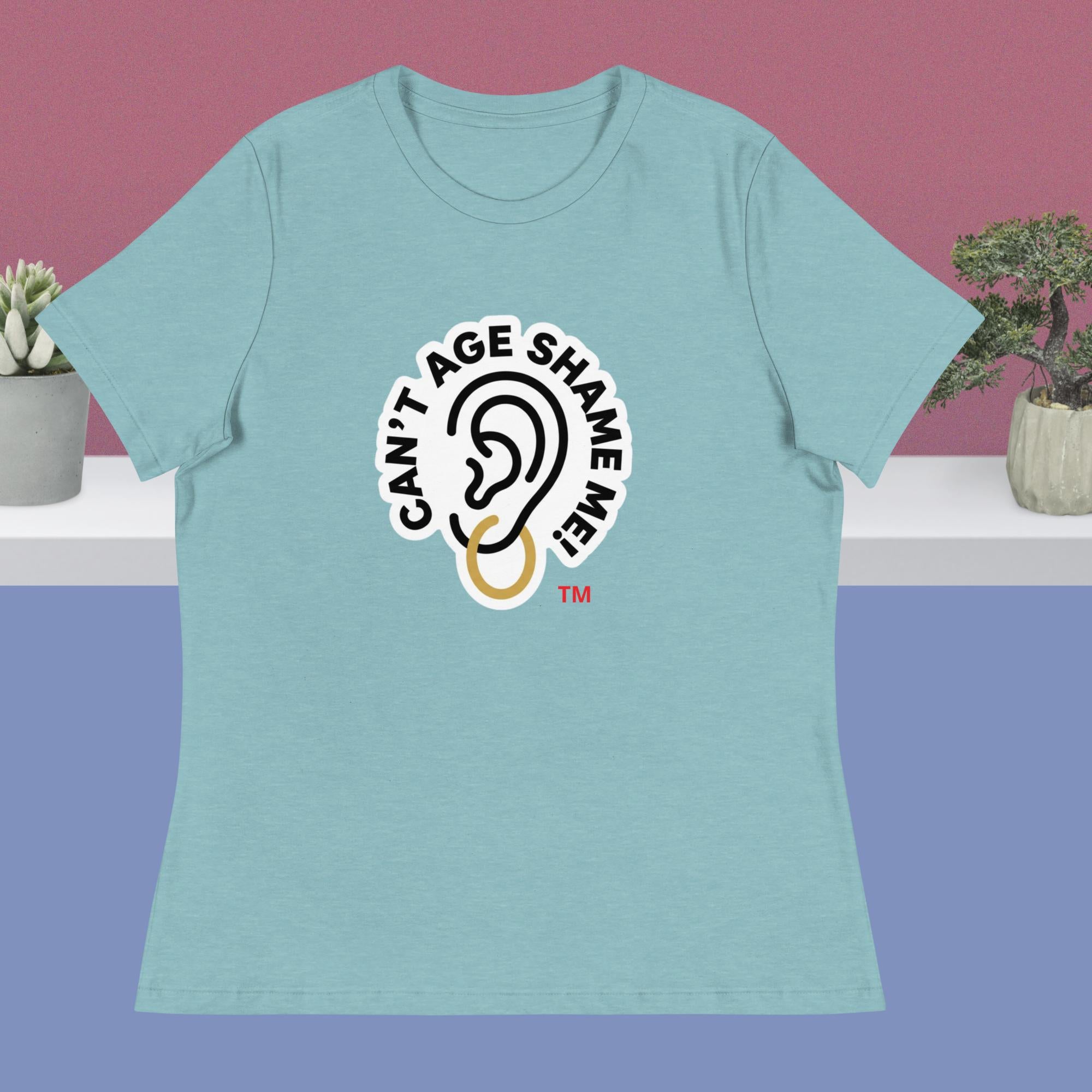 Light blue t-shirt with 'Can't Age Shame Me' logo on a pink and purple gradient background.