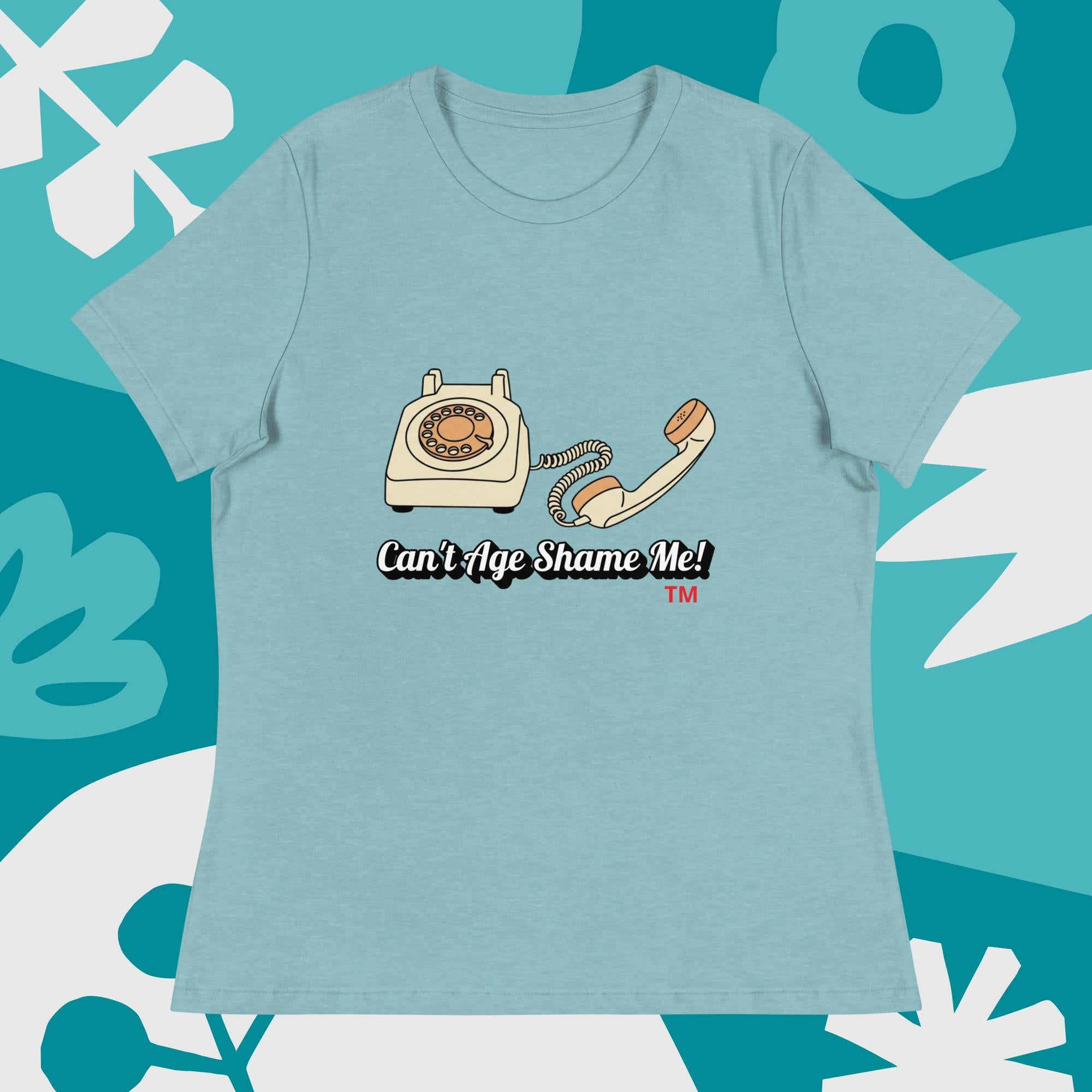 heather blue lagoon  t-shirt with vintage phone graphic and 'Can't Age Shame Me!' text on a teal background with white abstract shapes.