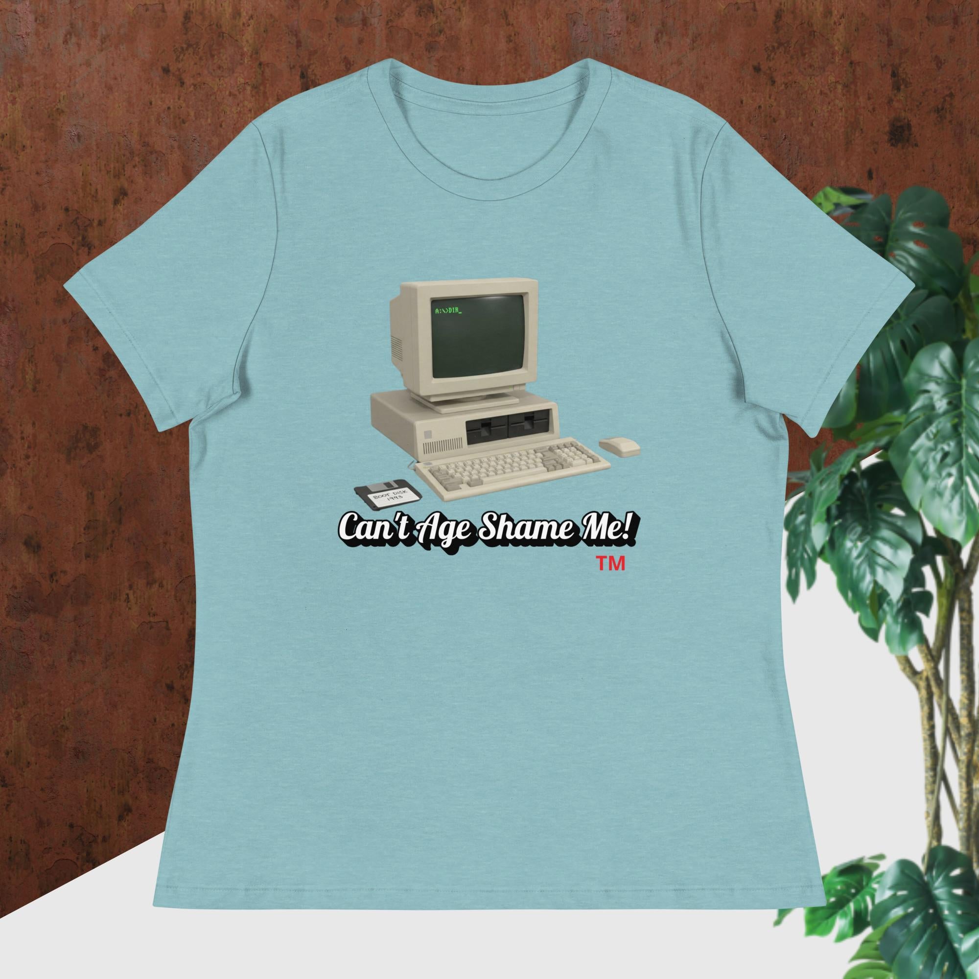 heather blue lagoon t-shirt with vintage computer graphic and text 'Can't Age Shame Me!' on a wooden surface.