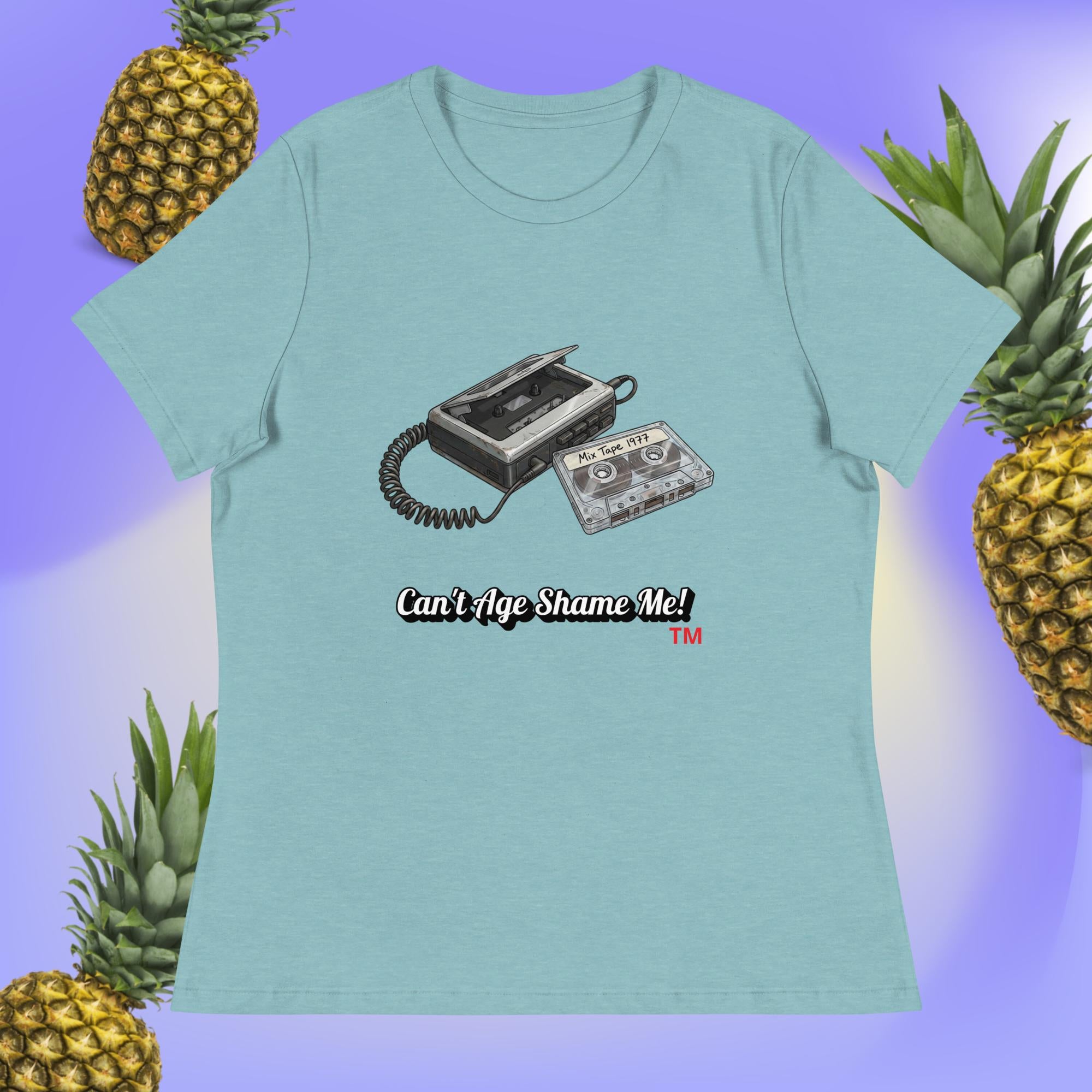 heather blue lagoon t-shirt with a cassette tape design and text 'Can't Age Shame Me!' surrounded by pineapples on a gradient background.