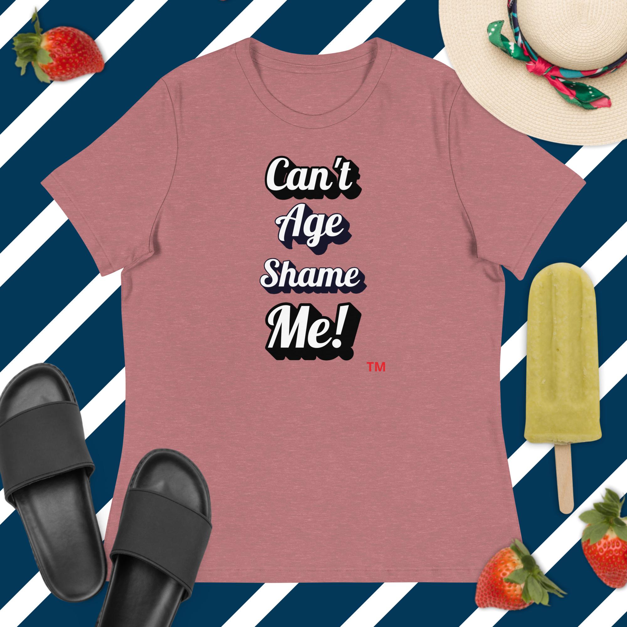 Pink t-shirt with 'Can't Age Shame Me!' text on a blue and white striped background with accessories.
