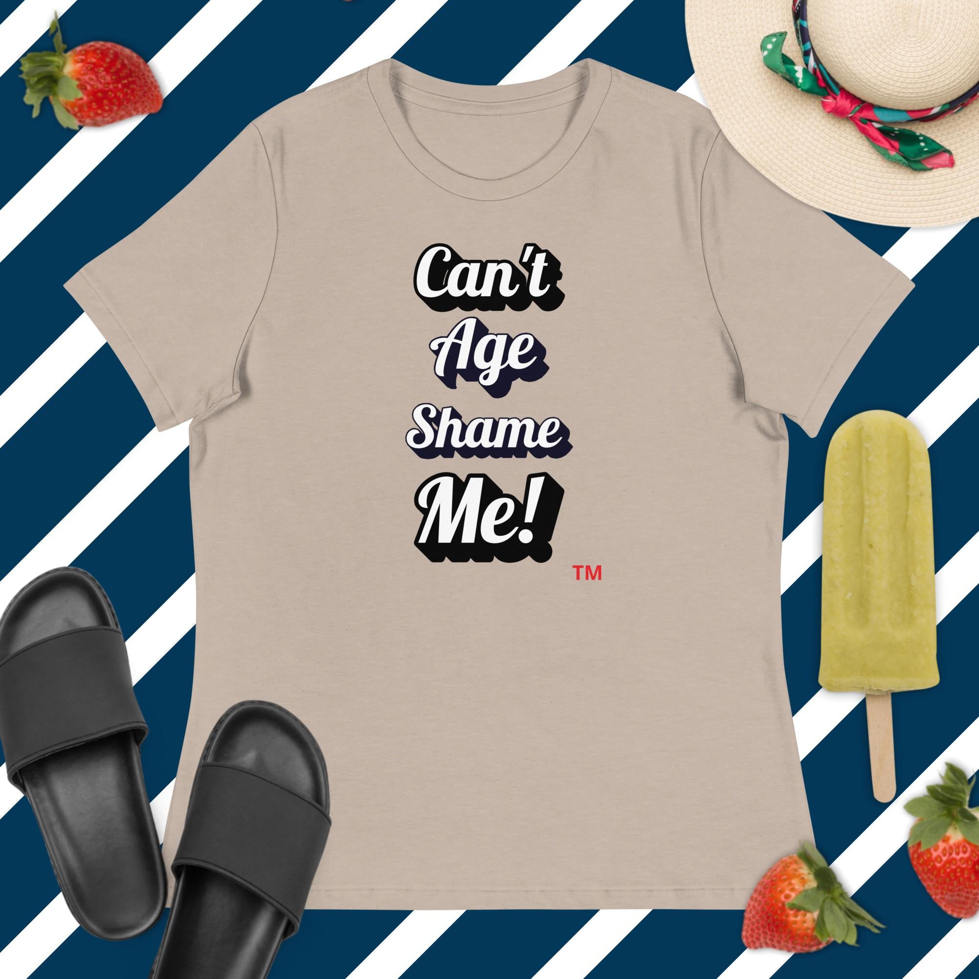 Beige t-shirt with 'Can't Age Shame Me!' text, black slides, green popsicle, and strawberries on a blue and white striped background.