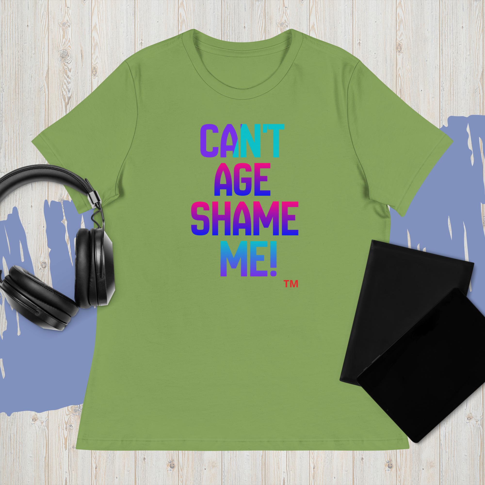 Green t-shirt with colorful text 'CAN'T AGE SHAME ME!' on a wooden surface with headphones and a black pouch.