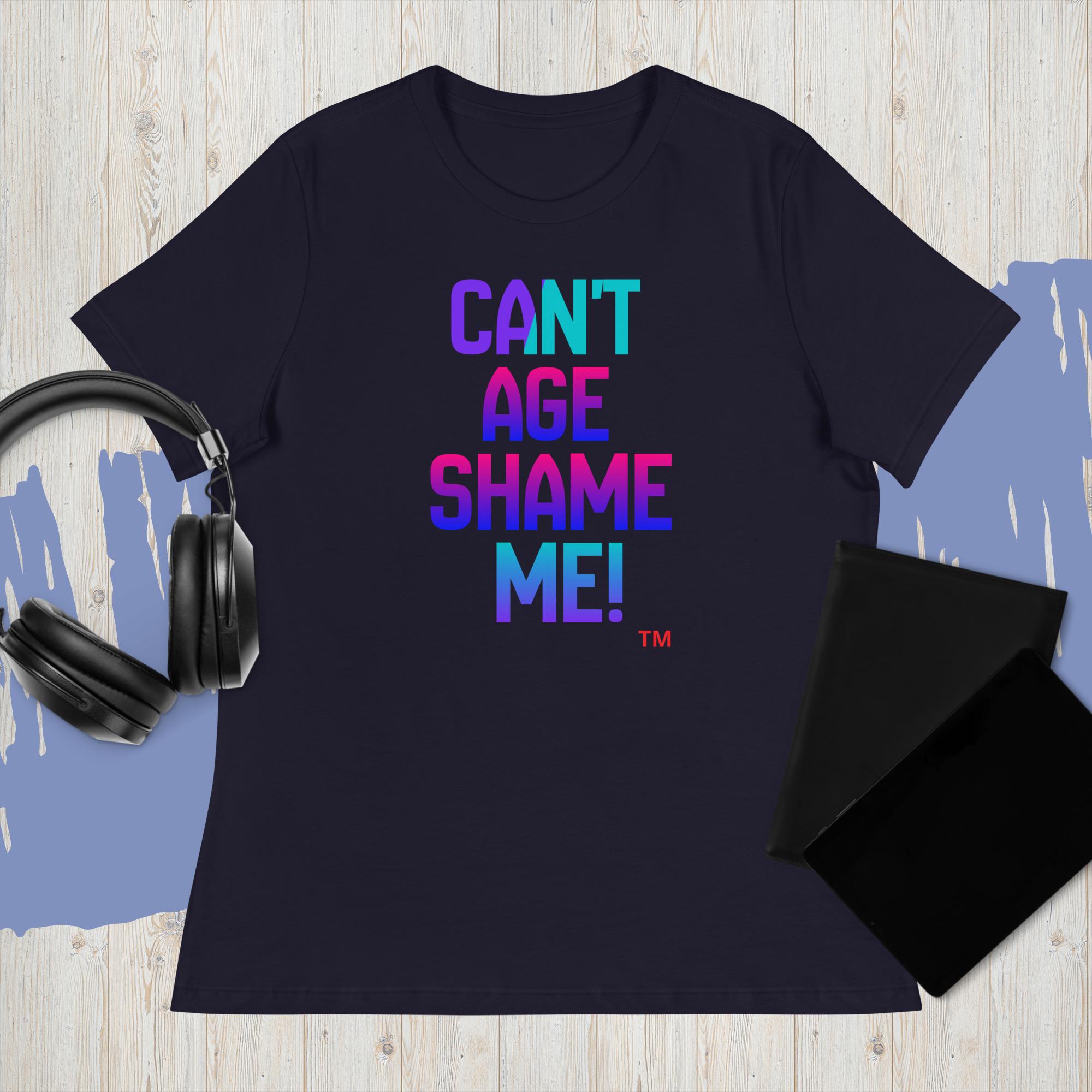 Black t-shirt with colorful text 'CAN'T AGE SHAME ME!' on a wooden surface with headphones and a black pouch.
