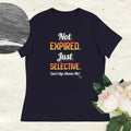 Navy t-shirt with colorful text on a light wooden surface with flowers.