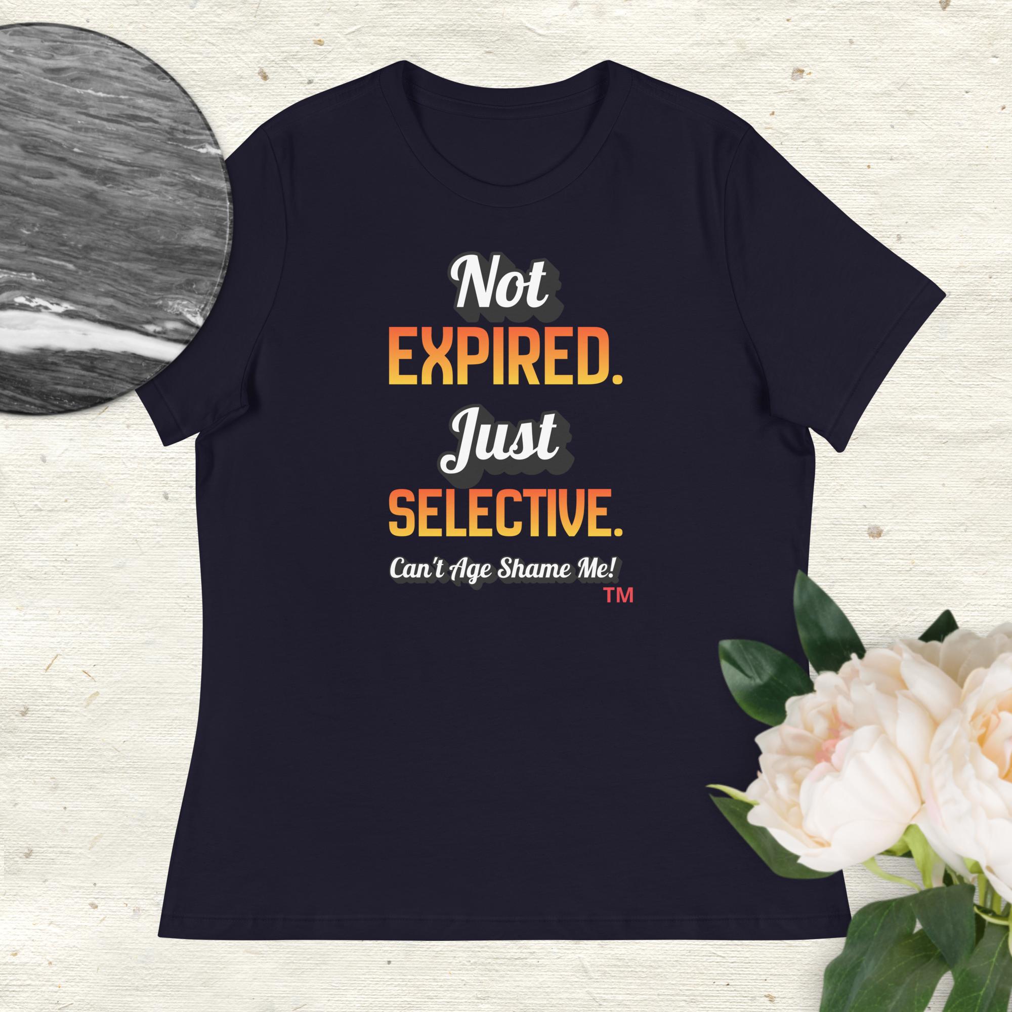 Navy t-shirt with colorful text on a light wooden surface with flowers.