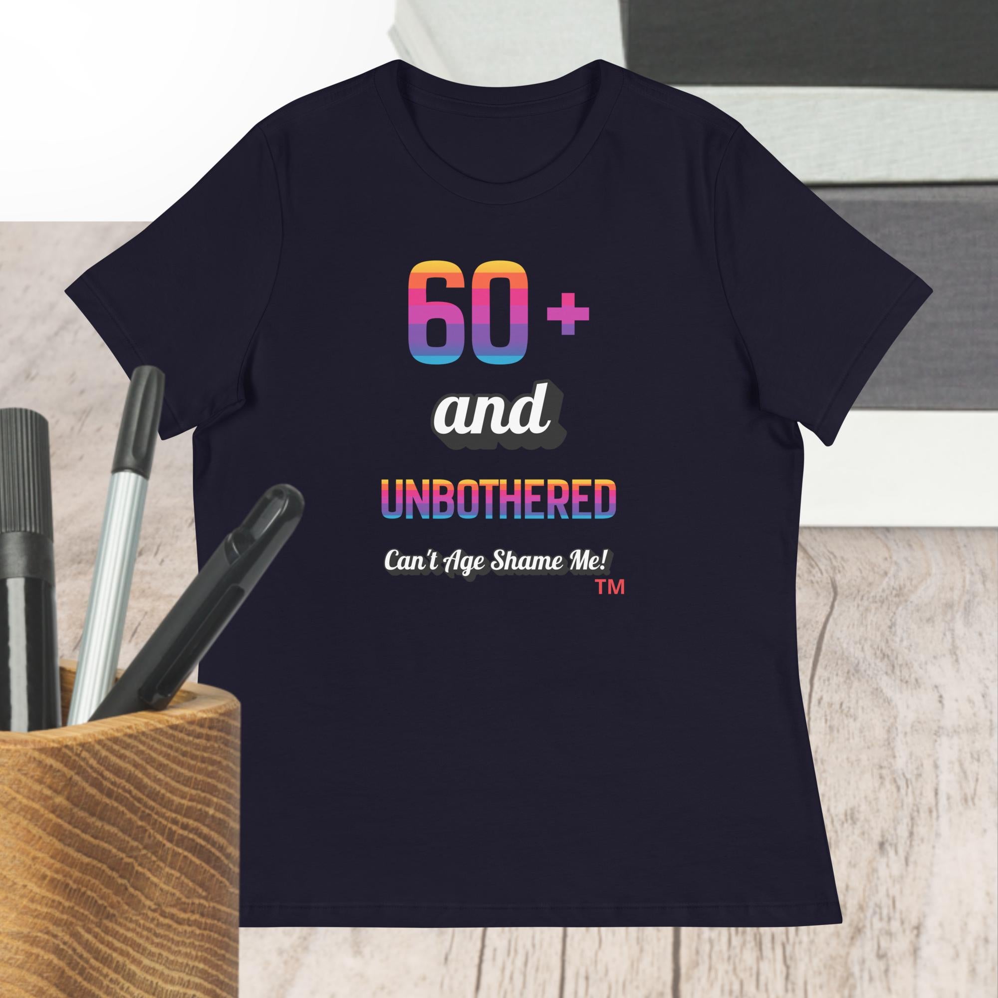 Navy t-shirt with colorful text design on a wooden surface with pens.