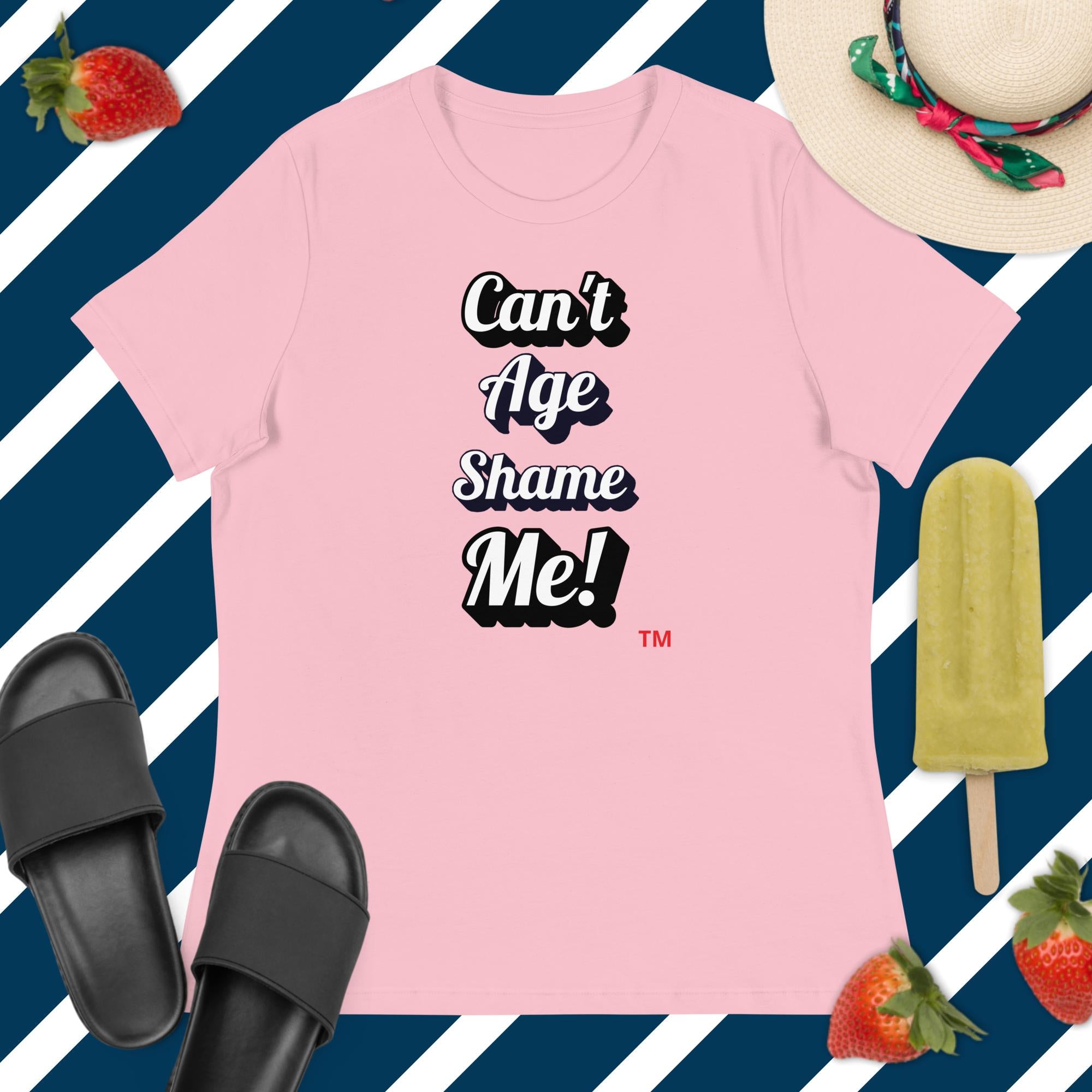Pink t-shirt with 'Can't Age Shame Me!' text on a blue and white striped background with accessories.
