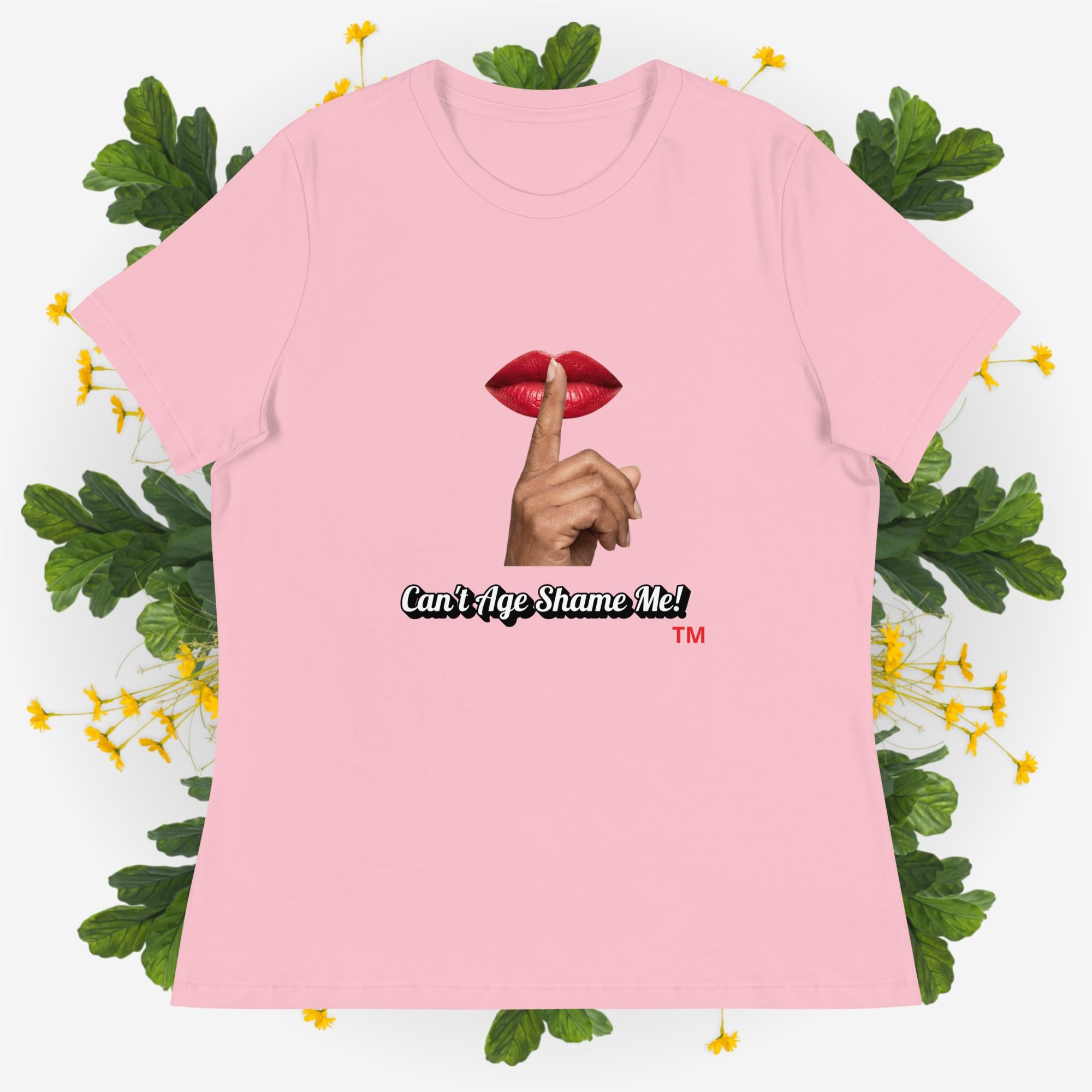 Pink t-shirt with graphic design and text 'Can't Age Shame Me' on a decorative background with leaves and flowers.