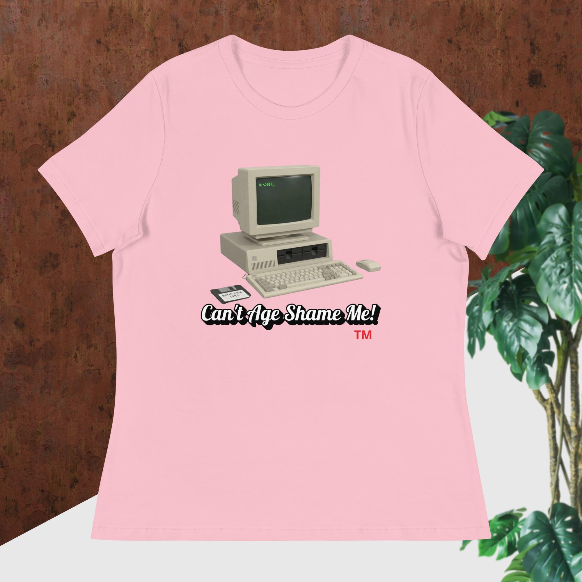 pink  t-shirt with vintage computer graphic and text 'Can't Age Shame Me!' on a wooden surface.